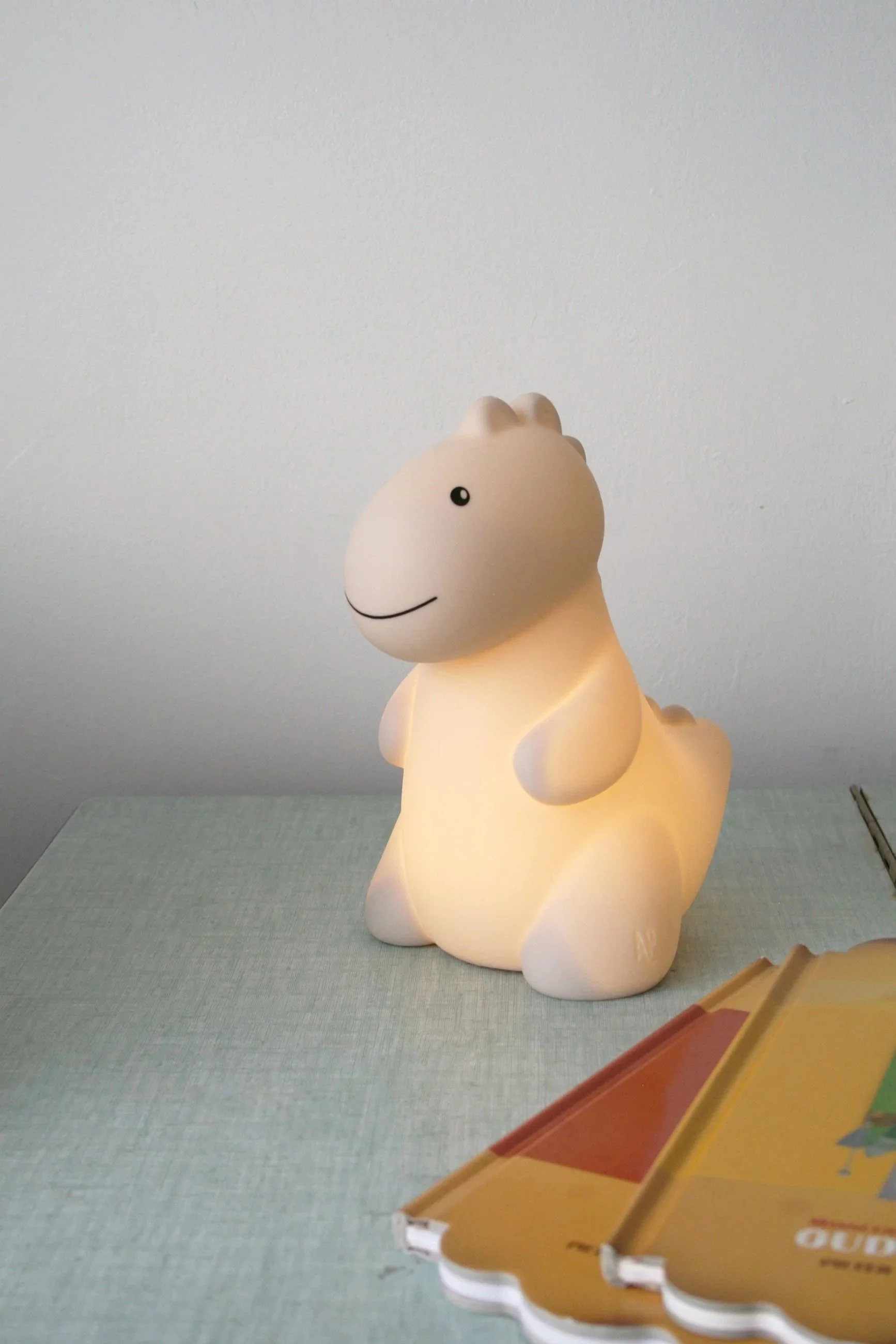 A cute plush lamp shaped like a smiling animal, sitting on a table.