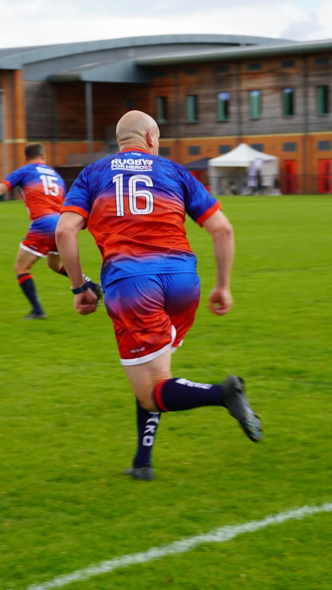 Rugby players in colorful jerseys running on a grassy field during a game.