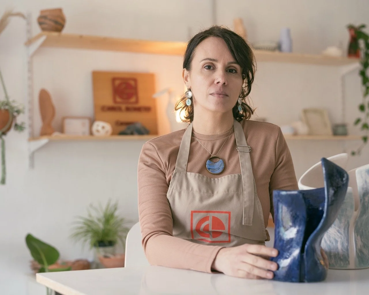 This portrait session with Carol embraces softness and stillness. Light, space, and subtle expression come together to create a peaceful, zen atmosphere. She has her hand on a dark blue ceramic sculpture that connect her creativity.