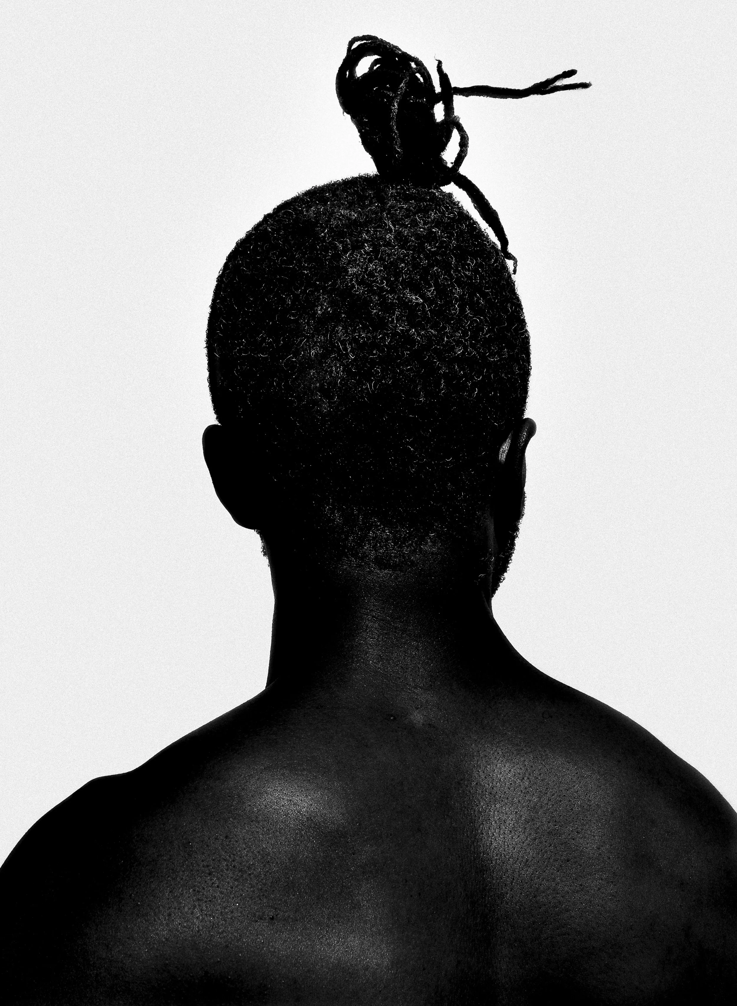 Back of a person's head with short curly hair, with a butterfly-shaped hairstyle accessory on top.