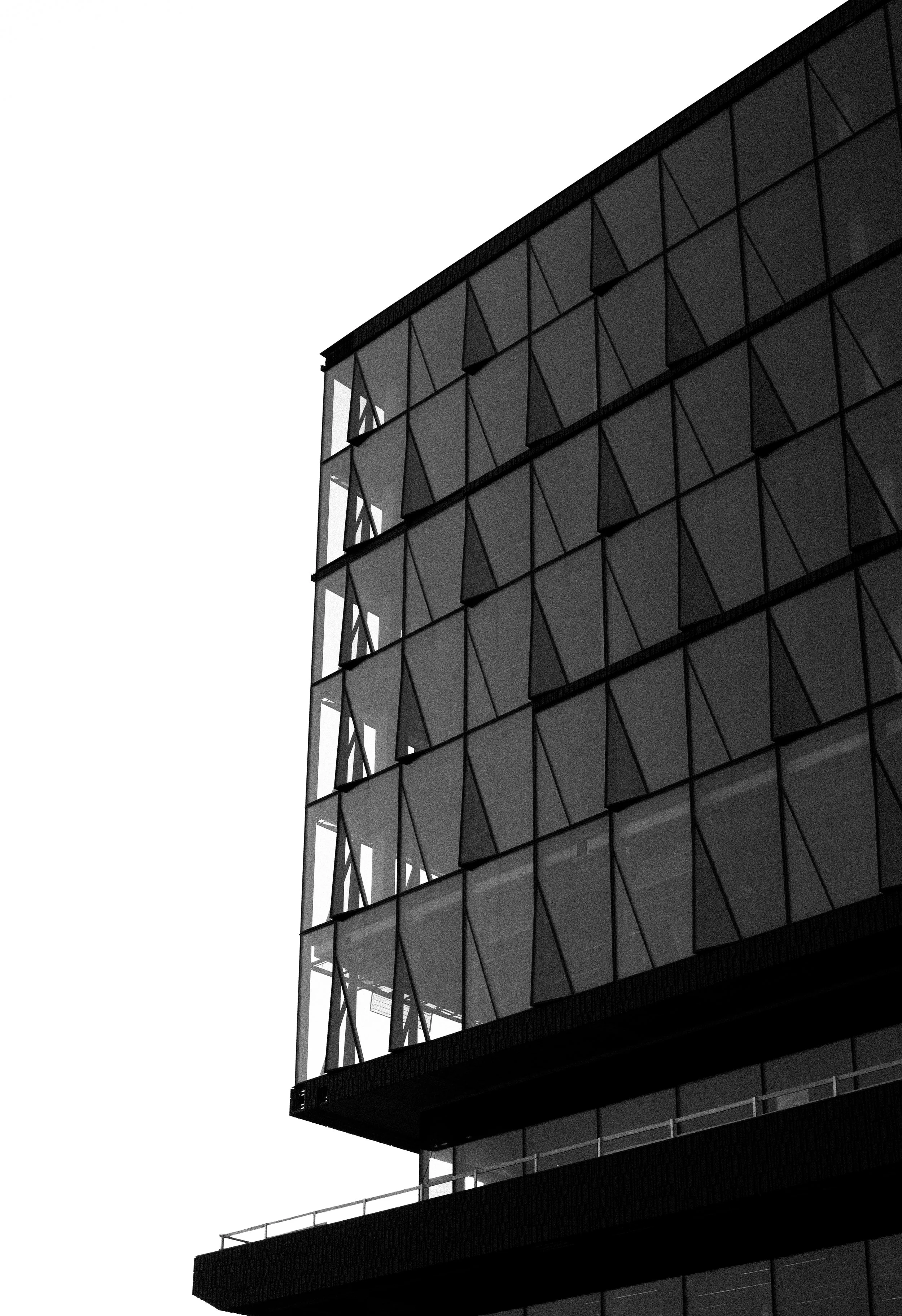 A modern glass building with a geometric facade, seen from a low angle.