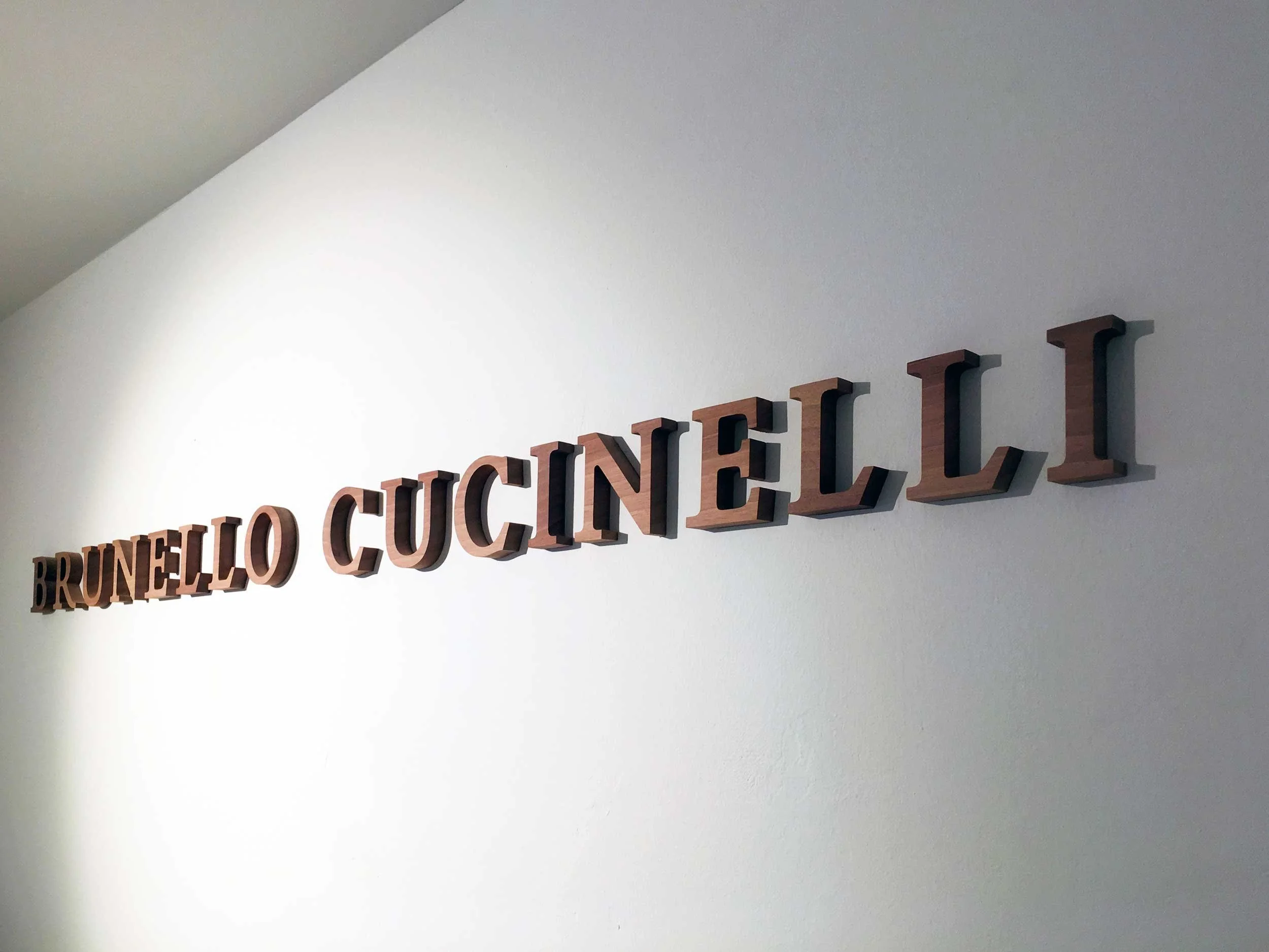 Wall-mounted wooden letters spelling out 'BRUNELLO CUCINE' on a white wall.