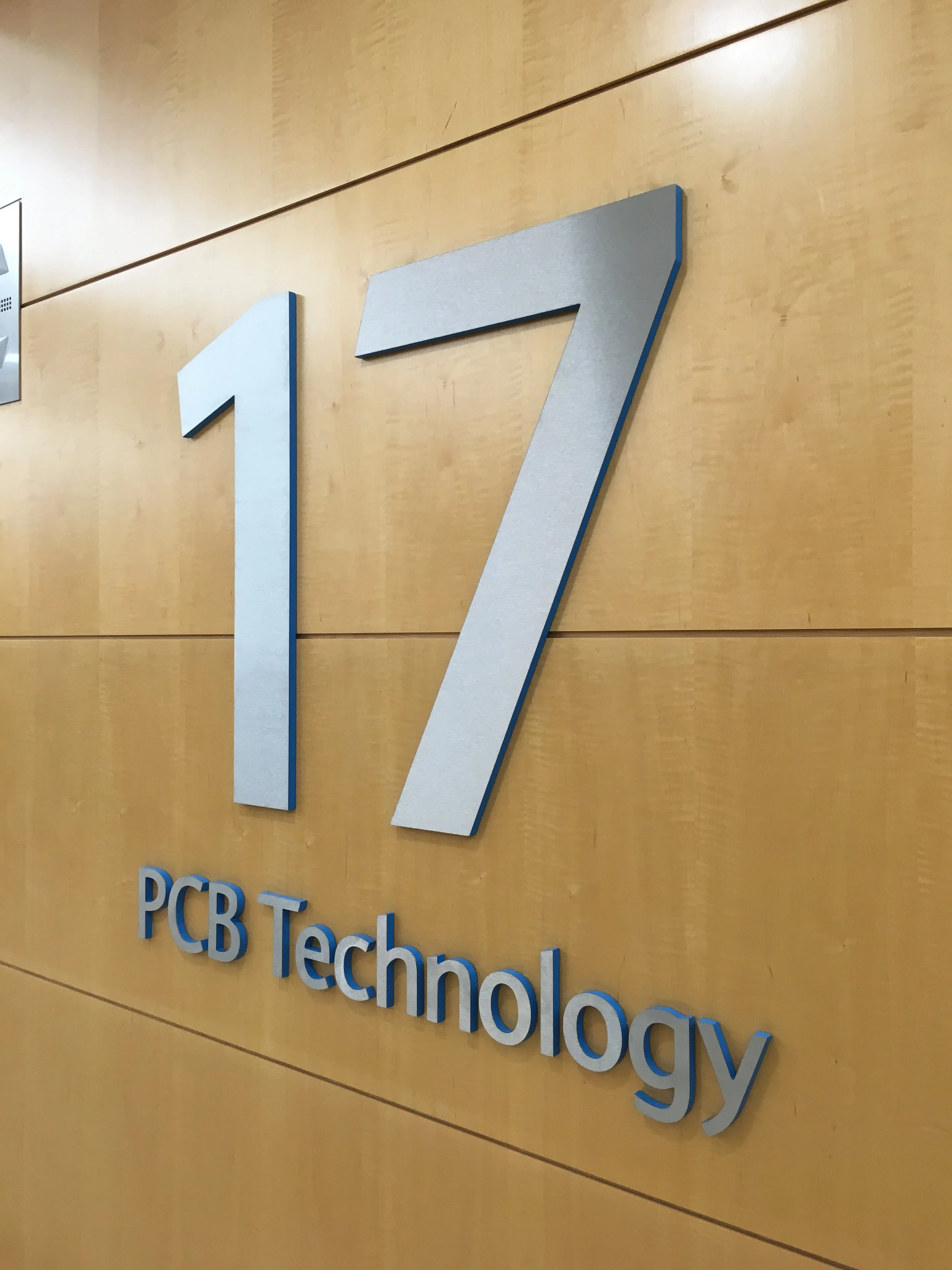 Company logo with large number '17' and the text 'PCB Technology' on a wooden wall.