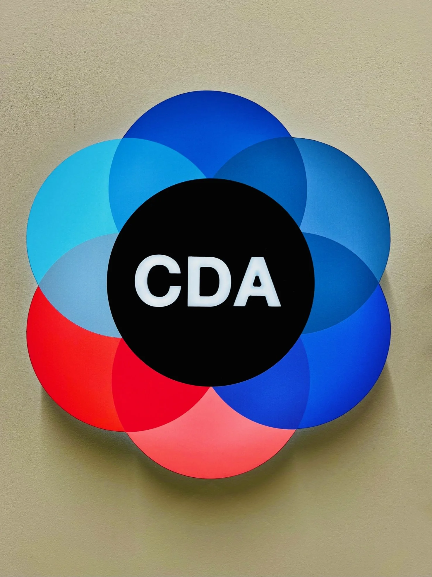 Colorful circular wall decoration with the black center featuring white text 'CDA'.