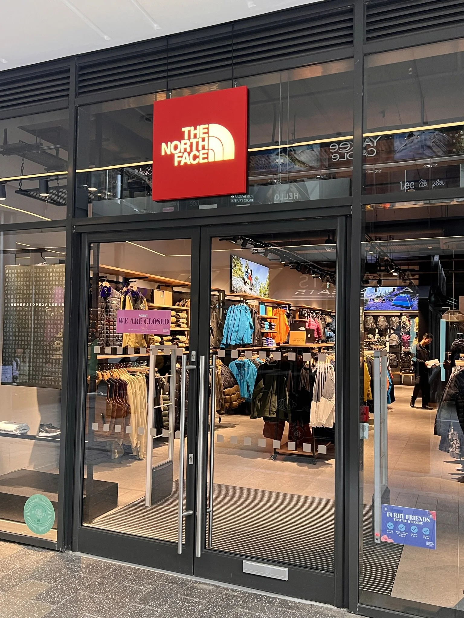 The North Face store entrance with store closed sign, showcasing outdoor clothing and gear inside.