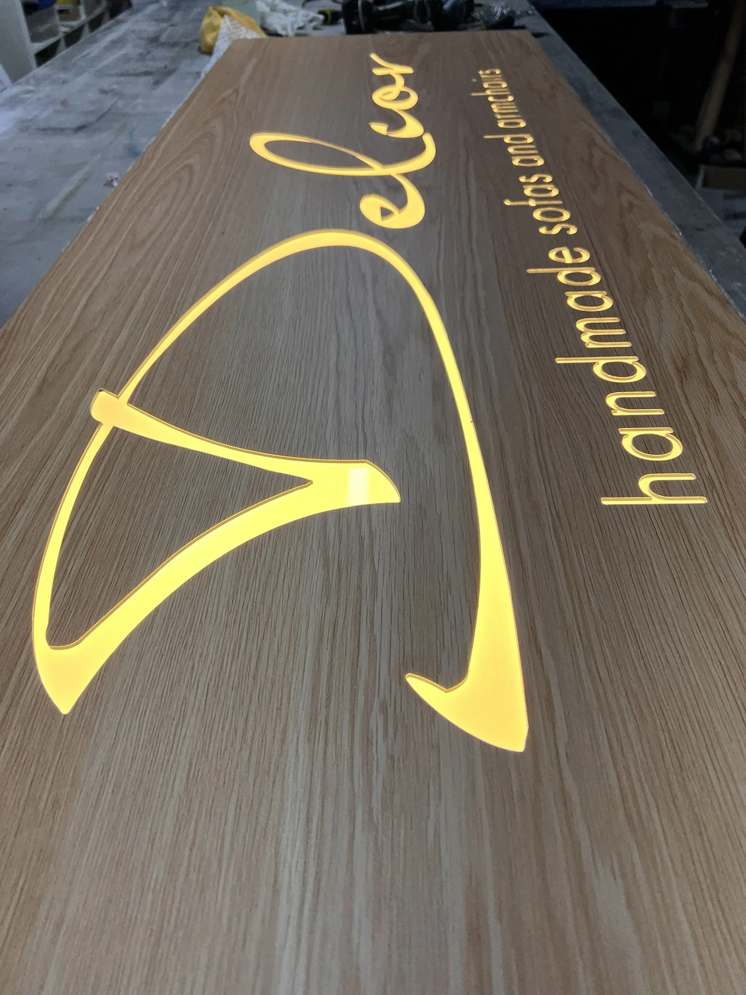 Wooden sign with illuminated yellow logo of a fox's head and the text 'håndmade shirts' and 'håndmade solid and quality'.