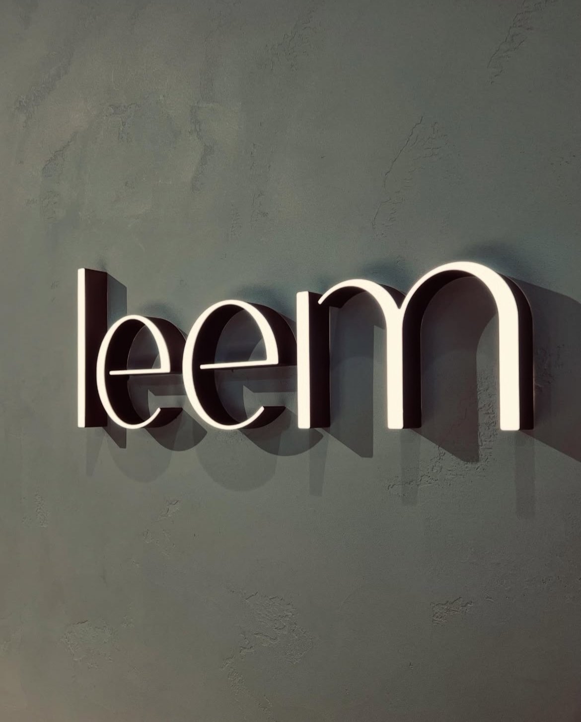Illuminated white neon sign spelling 'learn' on a gray wall.
