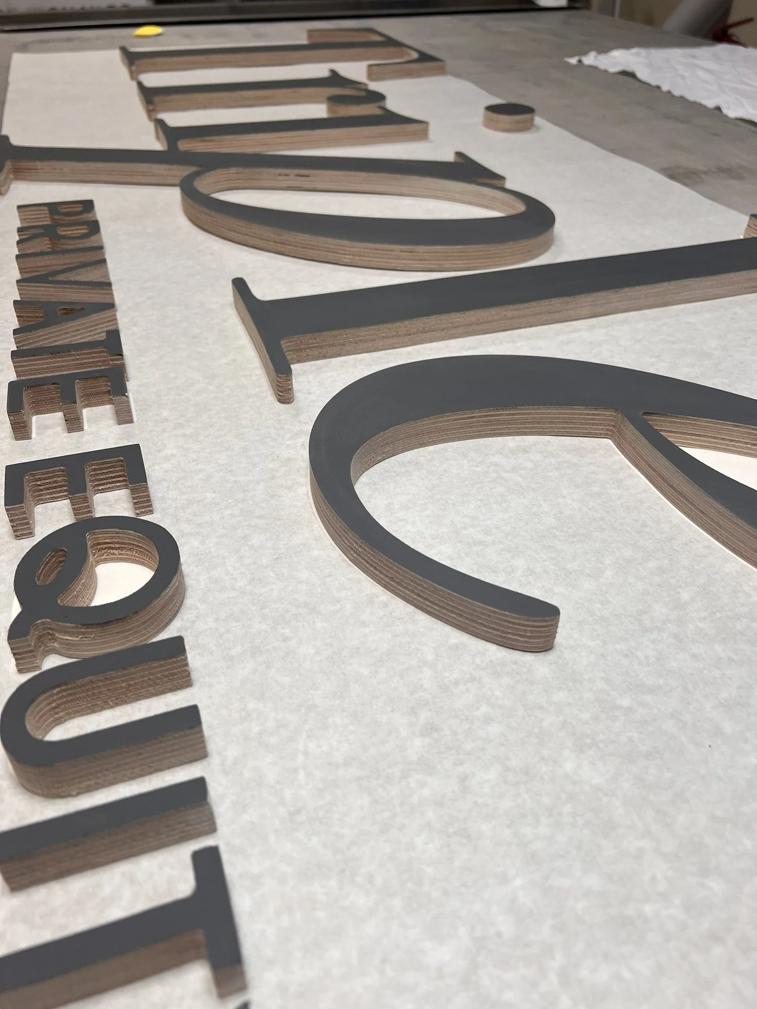 Close-up of layered wooden and black metal large 3D letters spelling 'CAFE' on a table.