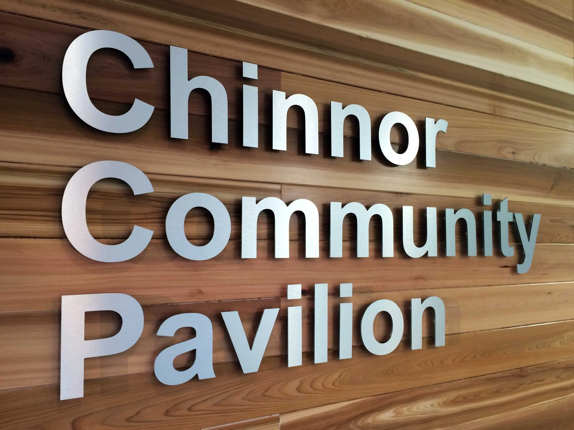 Sign reading 'Chinnor Community Pavilion' mounted on a wooden wall.