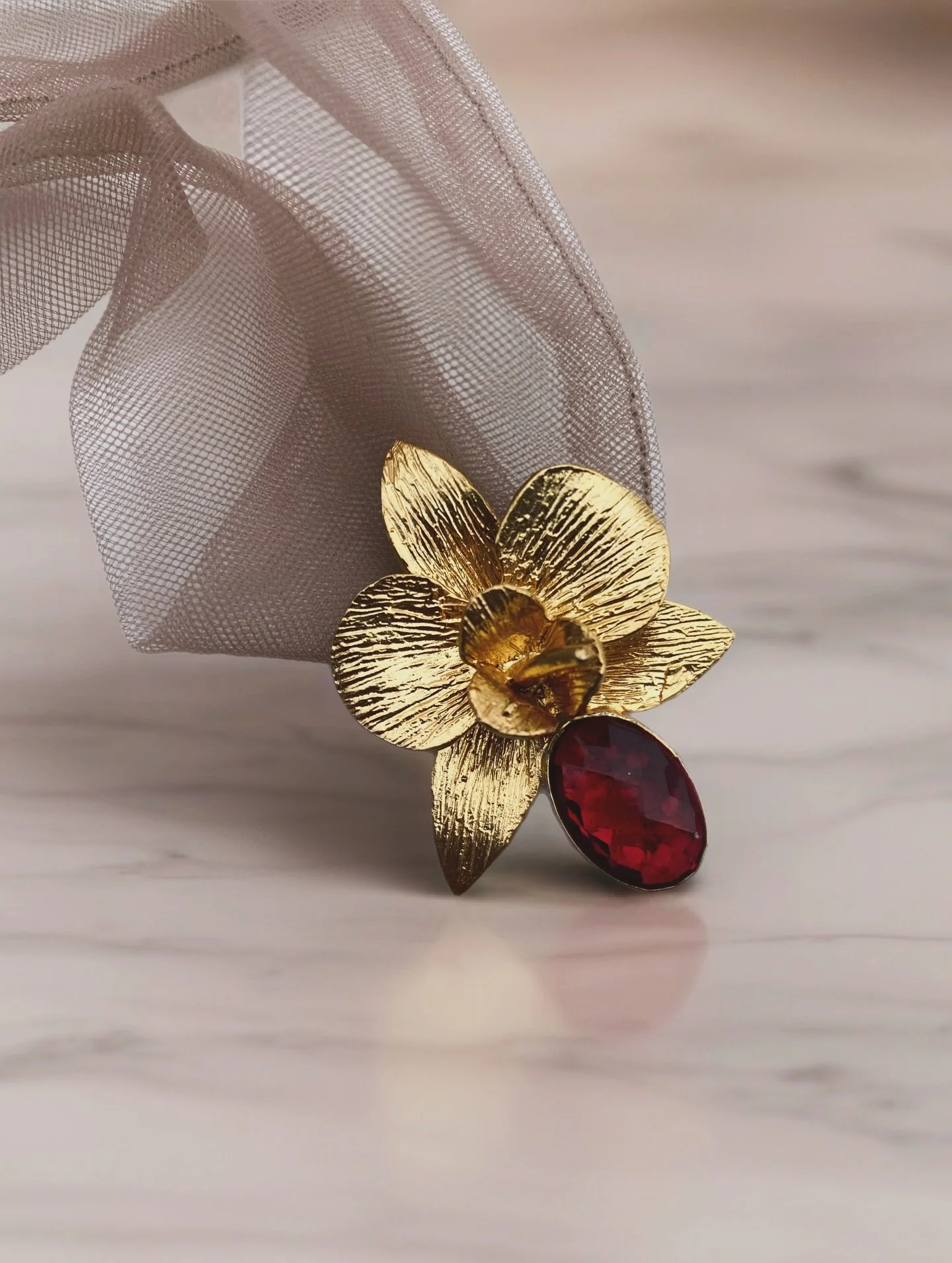 Little orchids pendants made of 24 karat gold brass metal and adorned with a glass crystal in its center, available in diffrent colors and with a mesh nude ribbon for an elgant style. #orchidjewelry #24kgoldjewellery #bridesmaidsjewelry #goldnecklace