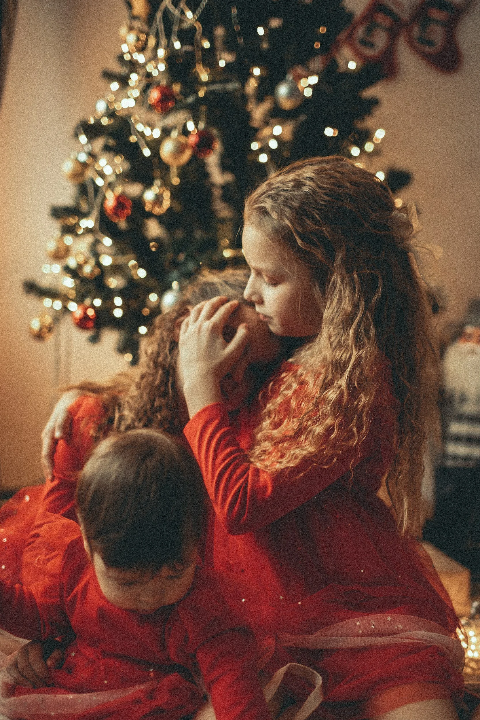 Children hugging in front of a tree