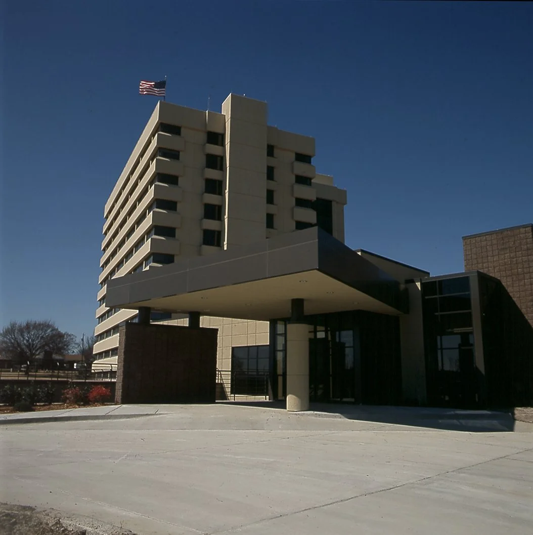 Exterior of Jane Phillips Surgical Hospital with an American flag on top, under a clear blue sky.