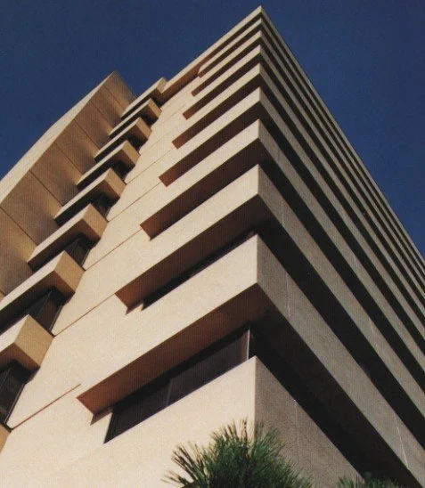 Low-angle view of a multi-story modern building against a clear blue sky.