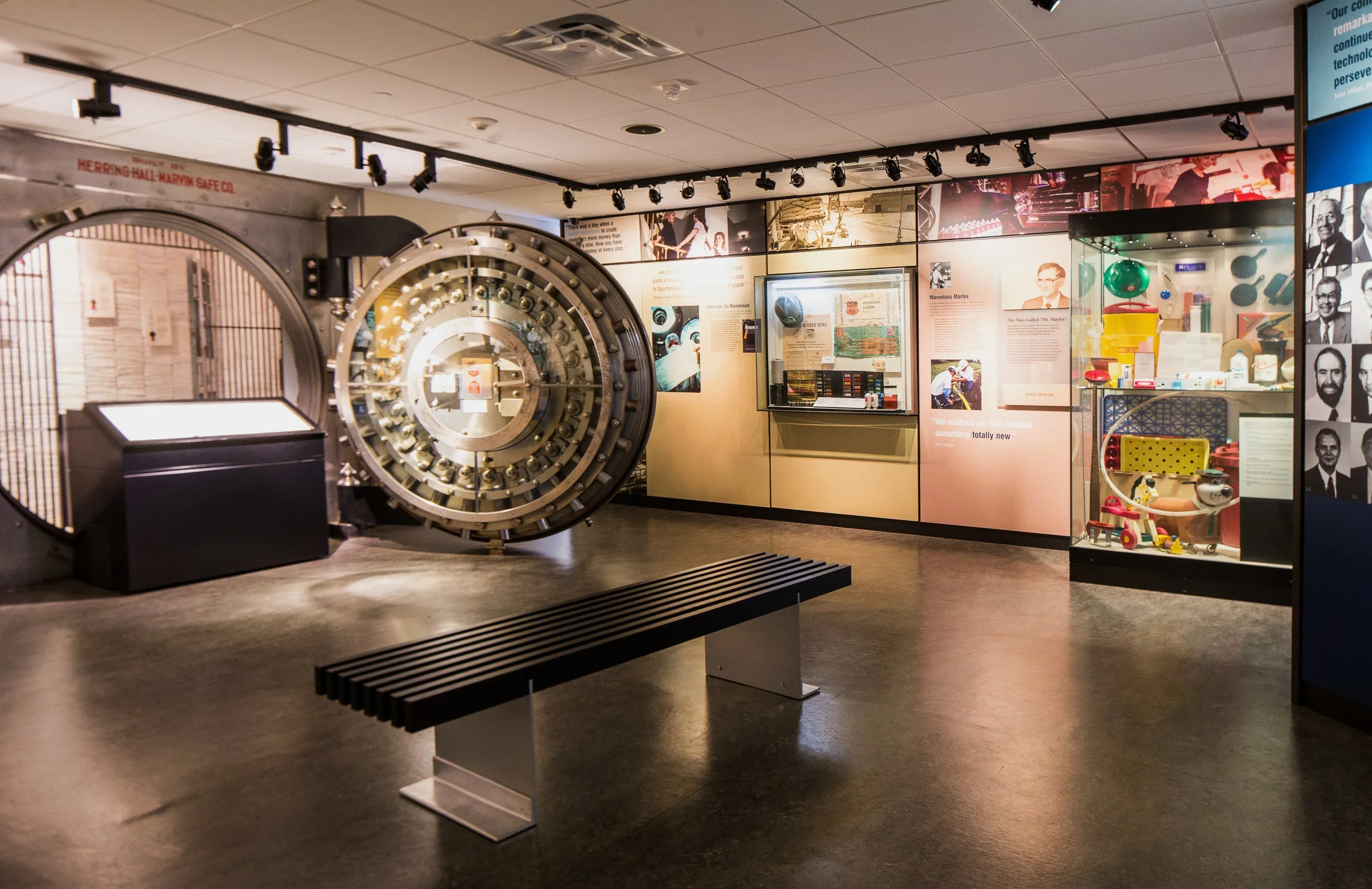 Museum exhibit featuring a large, round safe and display cases with historical artifacts and informational panels.
