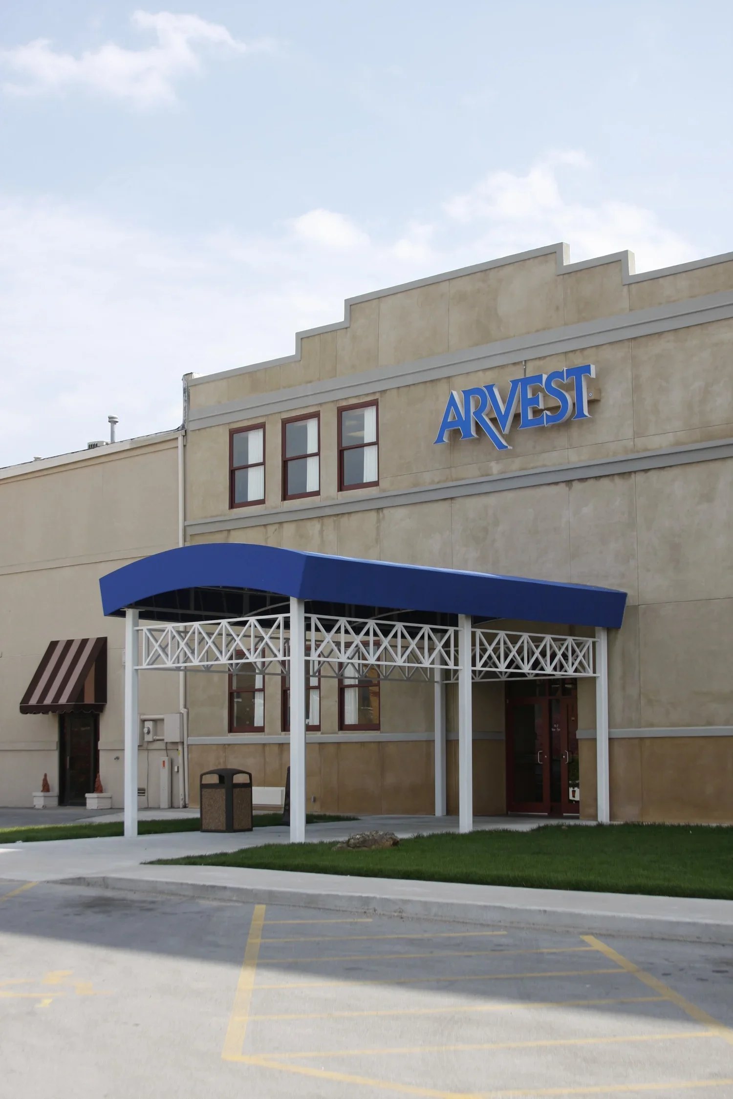 Exterior of Arvest Bank in Downtown Bartlesville, OK with a large blue sign that reads "ARVEST" and a blue awning over the entrance.