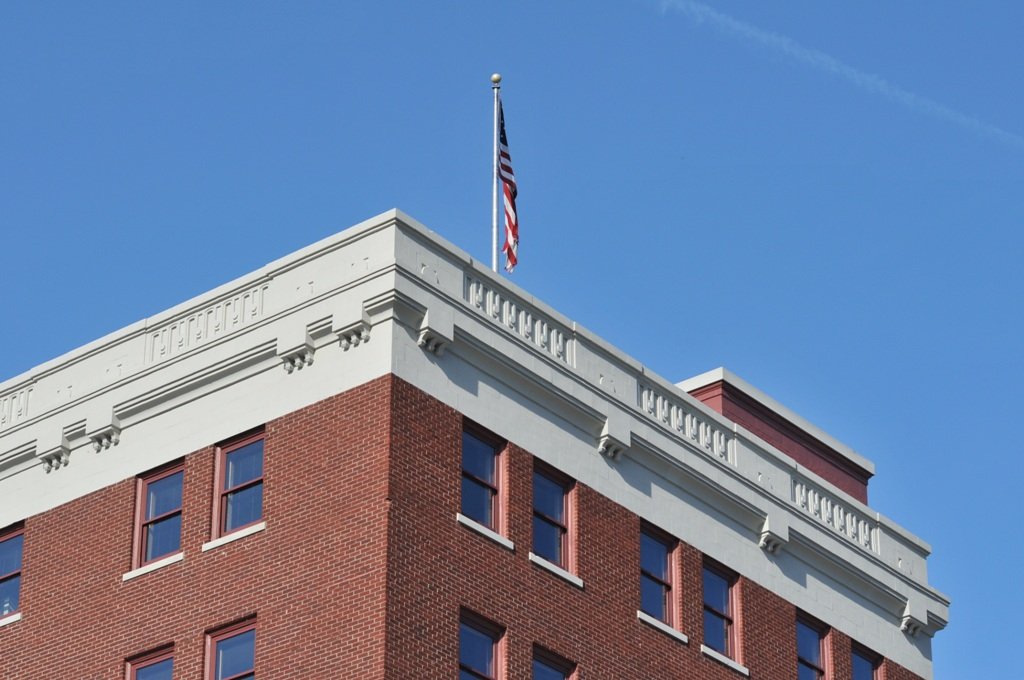 View of the top of a brick building with an American flag flying on a flagpole and the words 'HENRY M. JACKSON' on the white cornice.
