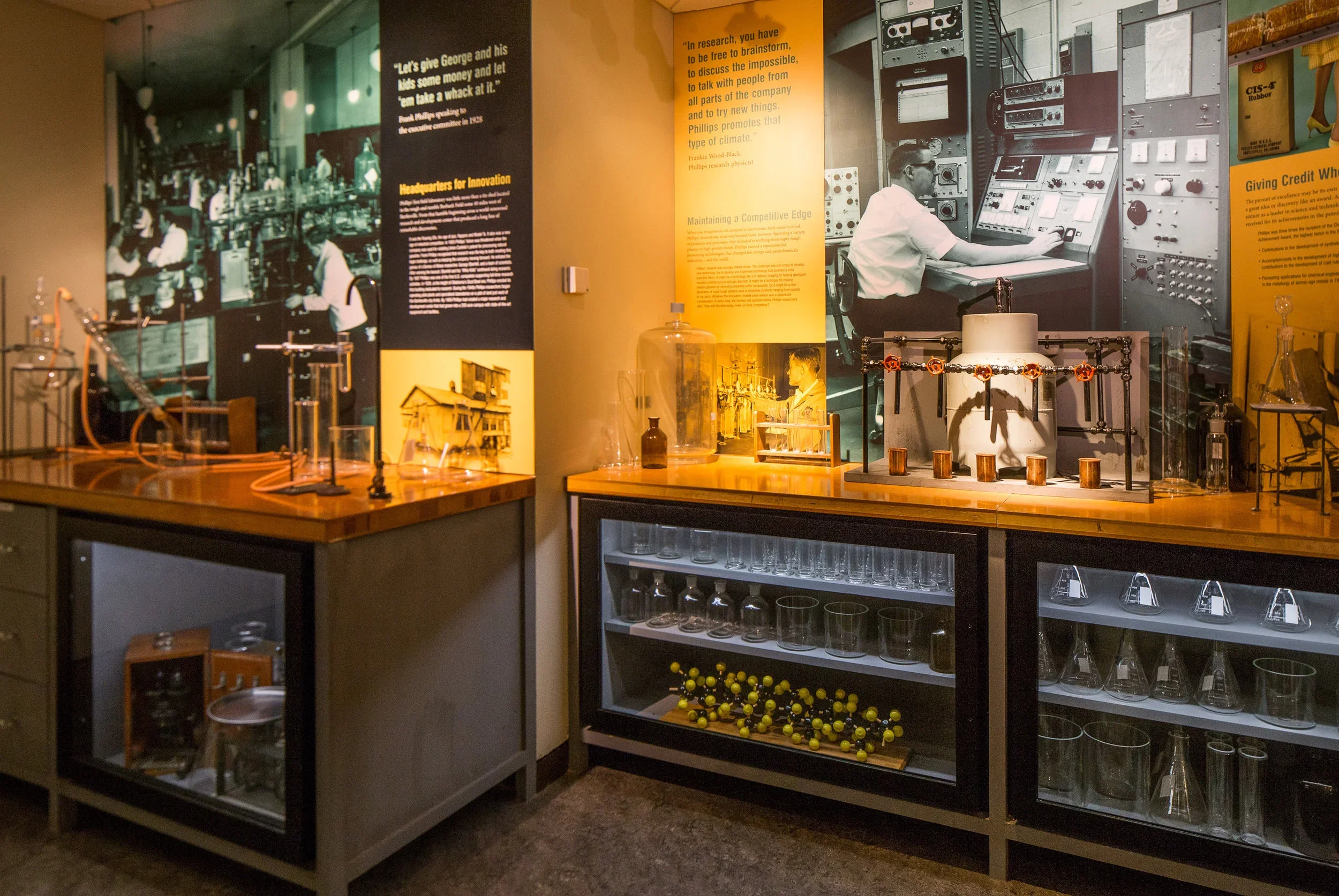Display of exhibits including scientific equipment, glassware, and informational posters in a museum showcasing the history of scientific research and technological innovation.