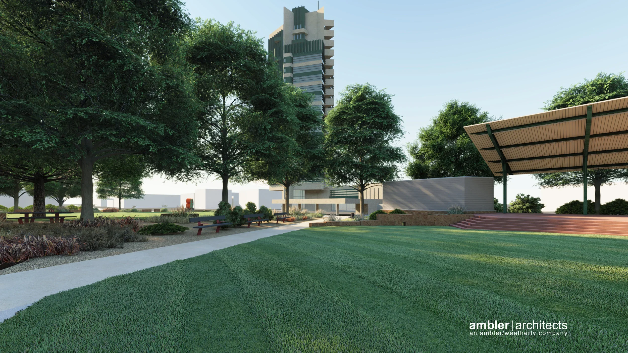 Landscape view of a park with green grass, large trees, concrete pathway, benches, and a modern building in the background, with a clear blue sky.