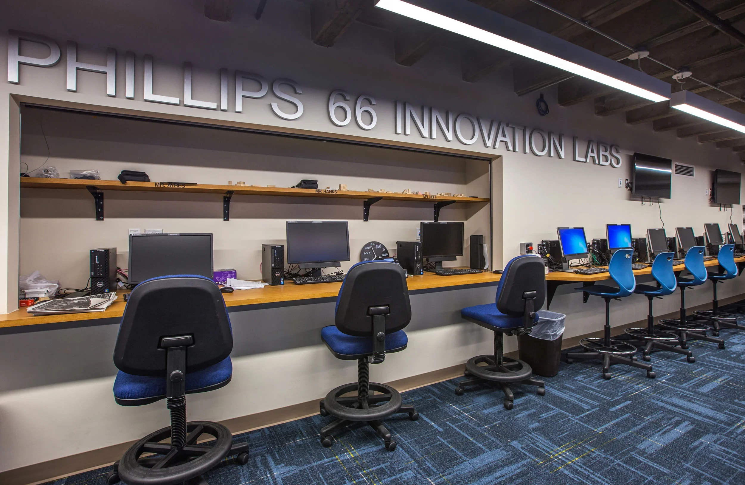Row of desktop computers and chairs in Phillips 66 Innovation Labs with a sign above reading 'PHILLIPS 66 INNOVATION LABS'.
