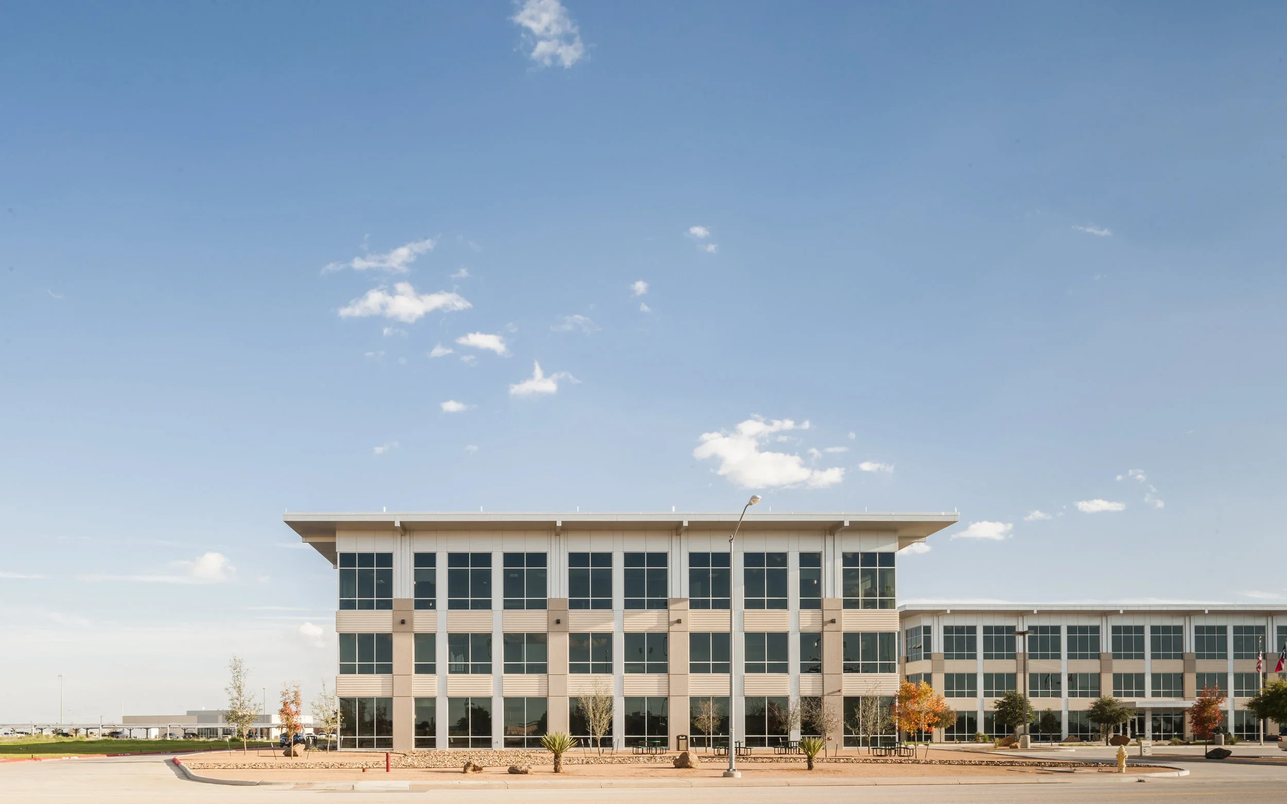 Exterior of EOG Midland Headquarters Building II with large glass windows, trees, and a clear blue sky.