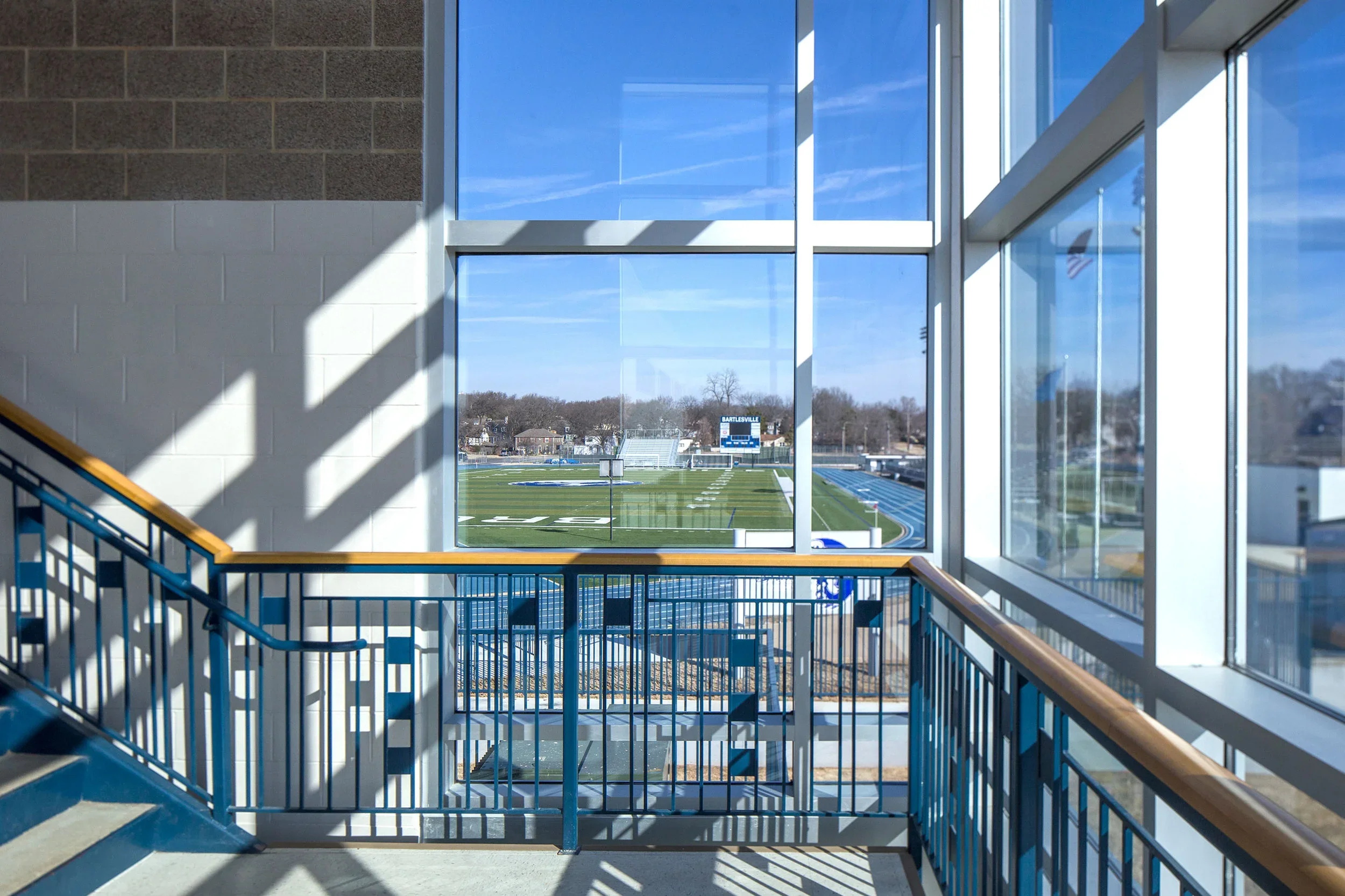 View of a football field through large windows from inside a stadium.