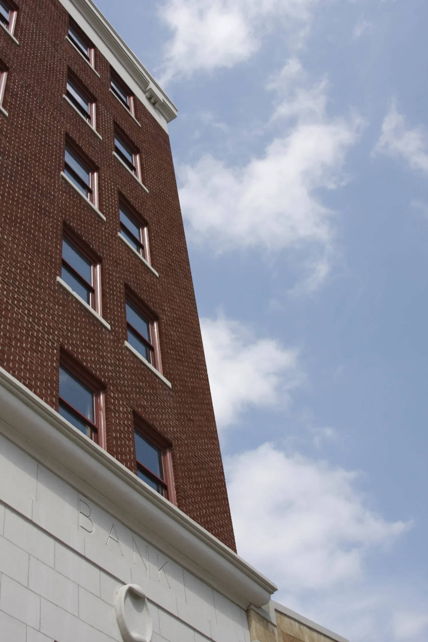 Low angle view of a red brick building against a partly cloudy sky.