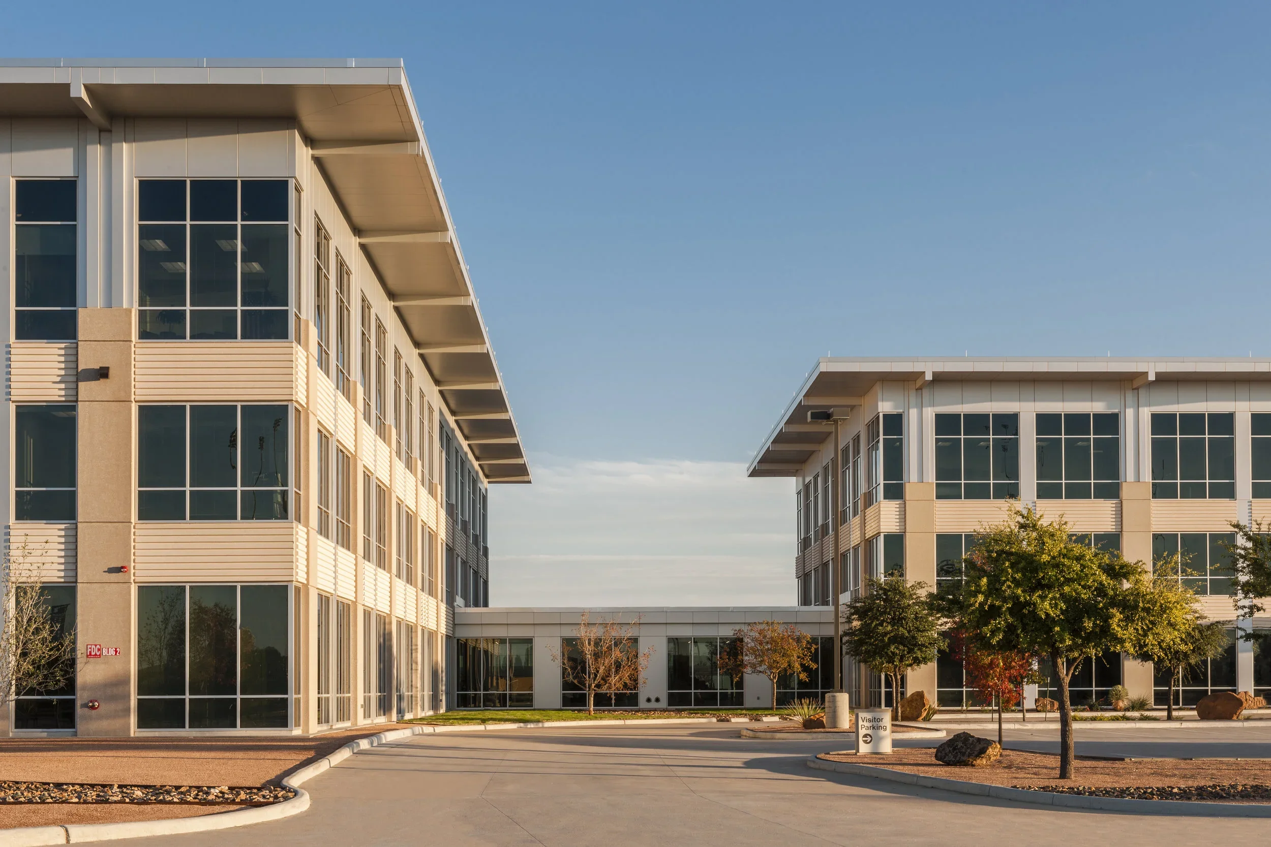 Exterior of EOG Midland Headquarters Building II with large glass windows, surrounded by a landscaped parking lot with small trees.