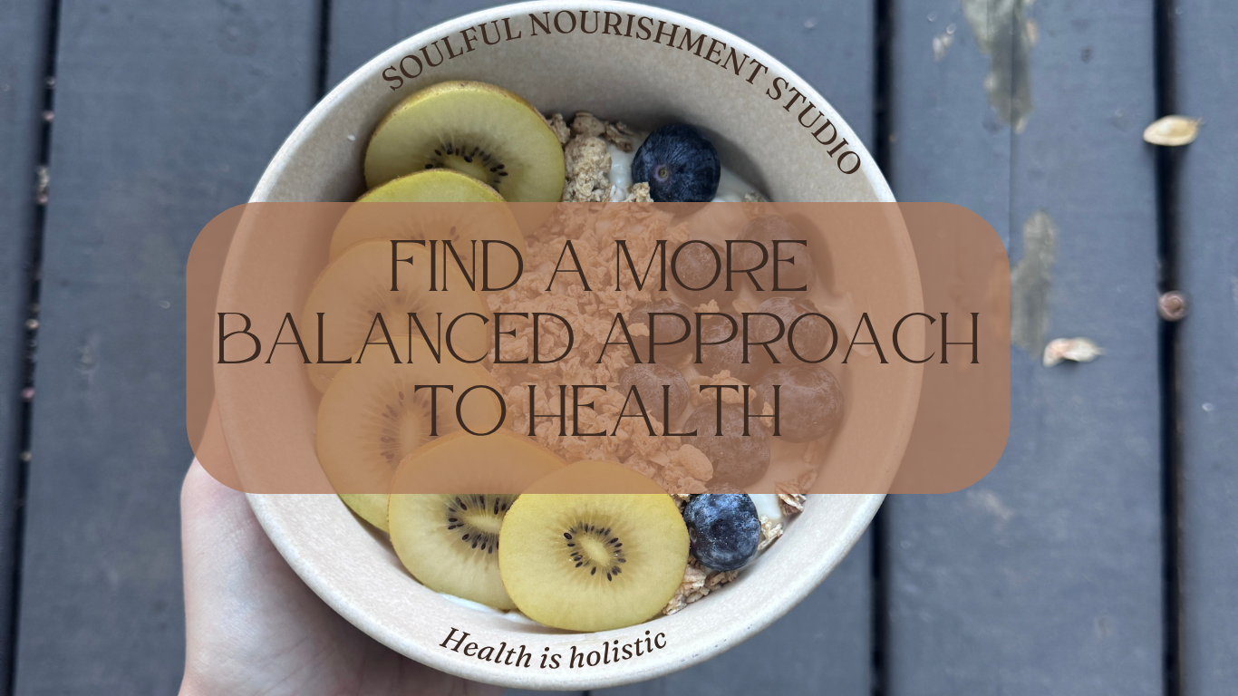 A bowl of yogurt topped with sliced kiwi, blueberries, and bananas, held in a person's hand outdoors on a wooden surface. Overlaid text reads, 'Find a more balanced approach to health.'