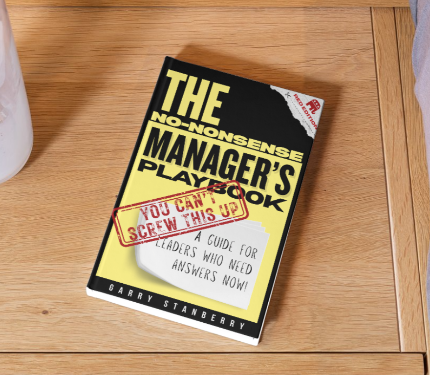 Book titled 'The No-Nonsense Manager's Playbook' by Garry Stanberry on a wooden table with a red stamp across the cover saying 'You Can't Screw This Up' and a note that reads 'A guide for leaders who need answers now!'