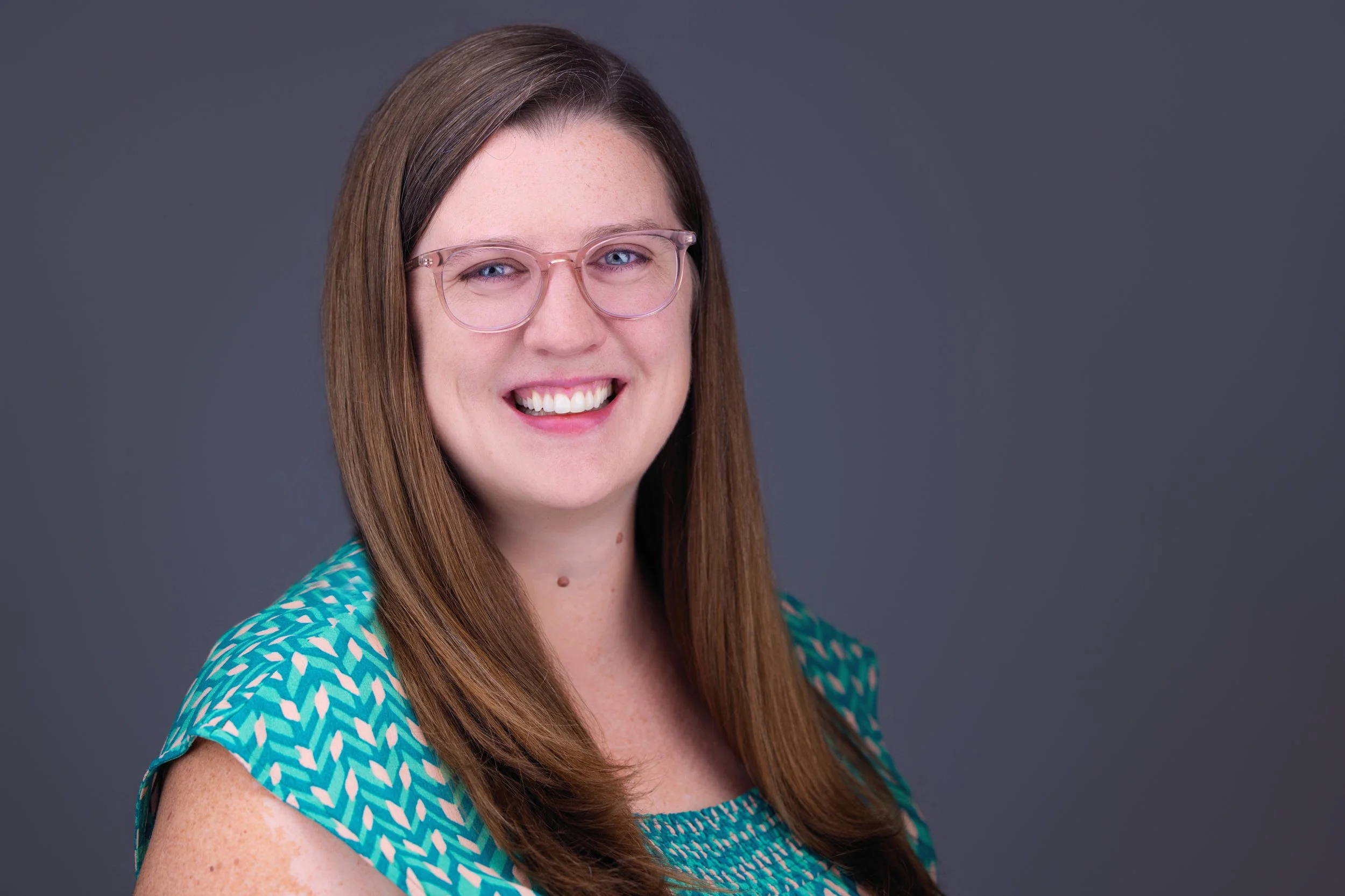Katelyn, smiling in green shirt against a grey background