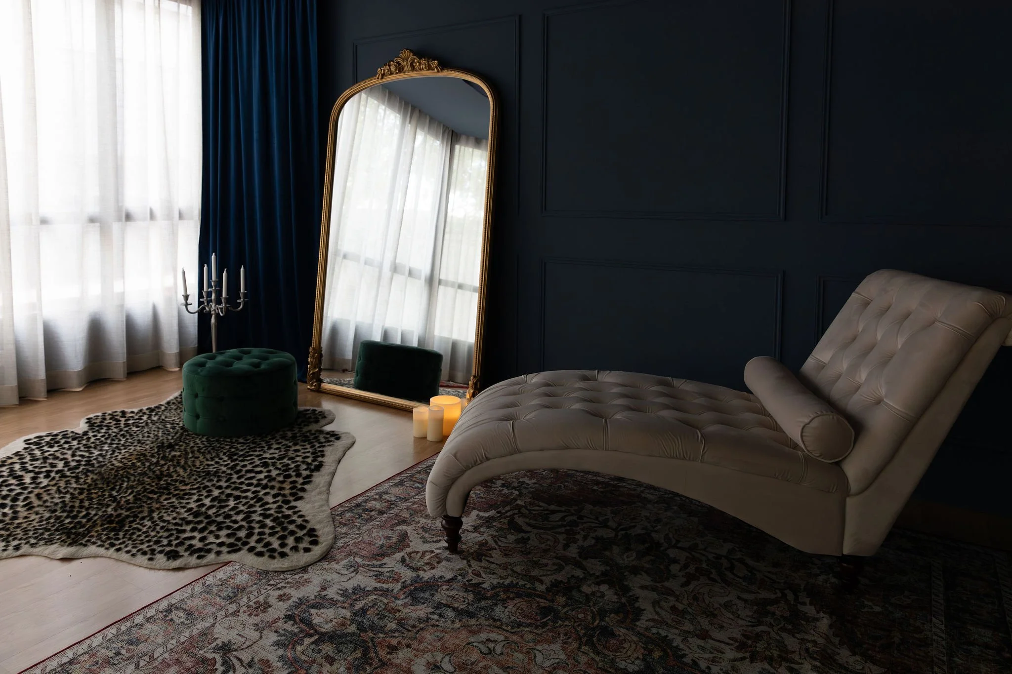 A woman with long, wavy hair lying on a bed with her eyes closed. She is wearing a lace top and a delicate necklace. One hand is resting on her forehead, and the other is near her face. The bed has a textured blanket and clothes nearby.