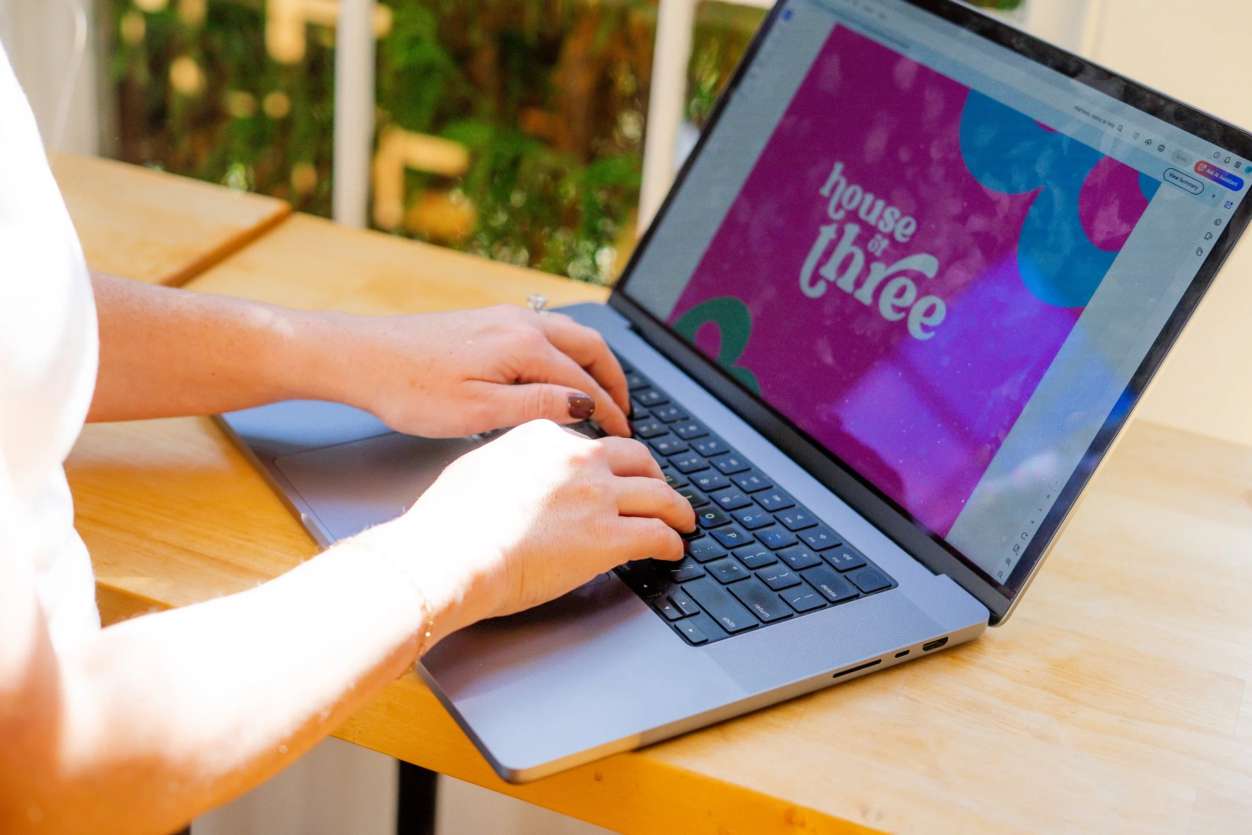Woman working on laptop with House of Three logo on it