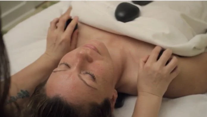 Person receiving a hot stone massage on their shoulders.