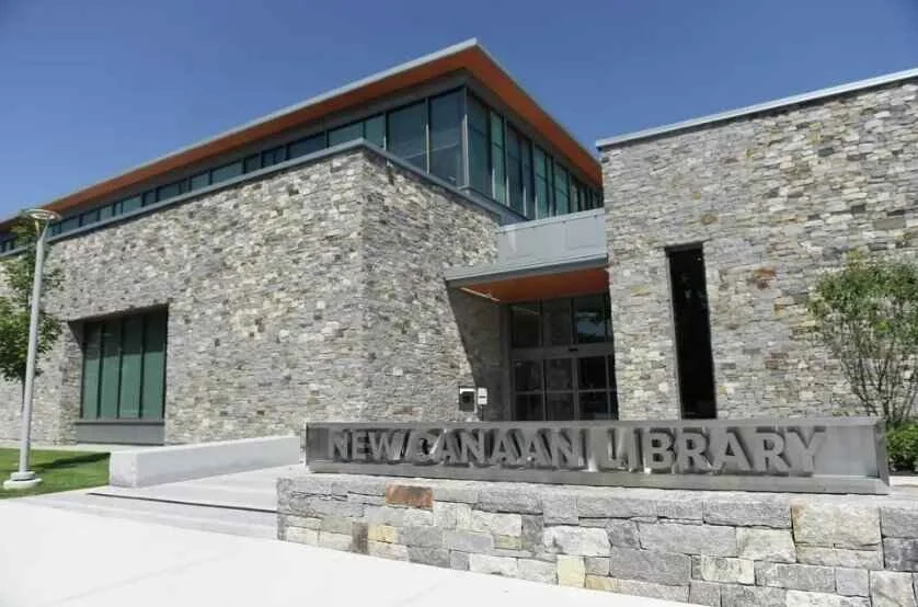 Modern library building made of stone with a sign that reads 'New Janaan Library' in front.