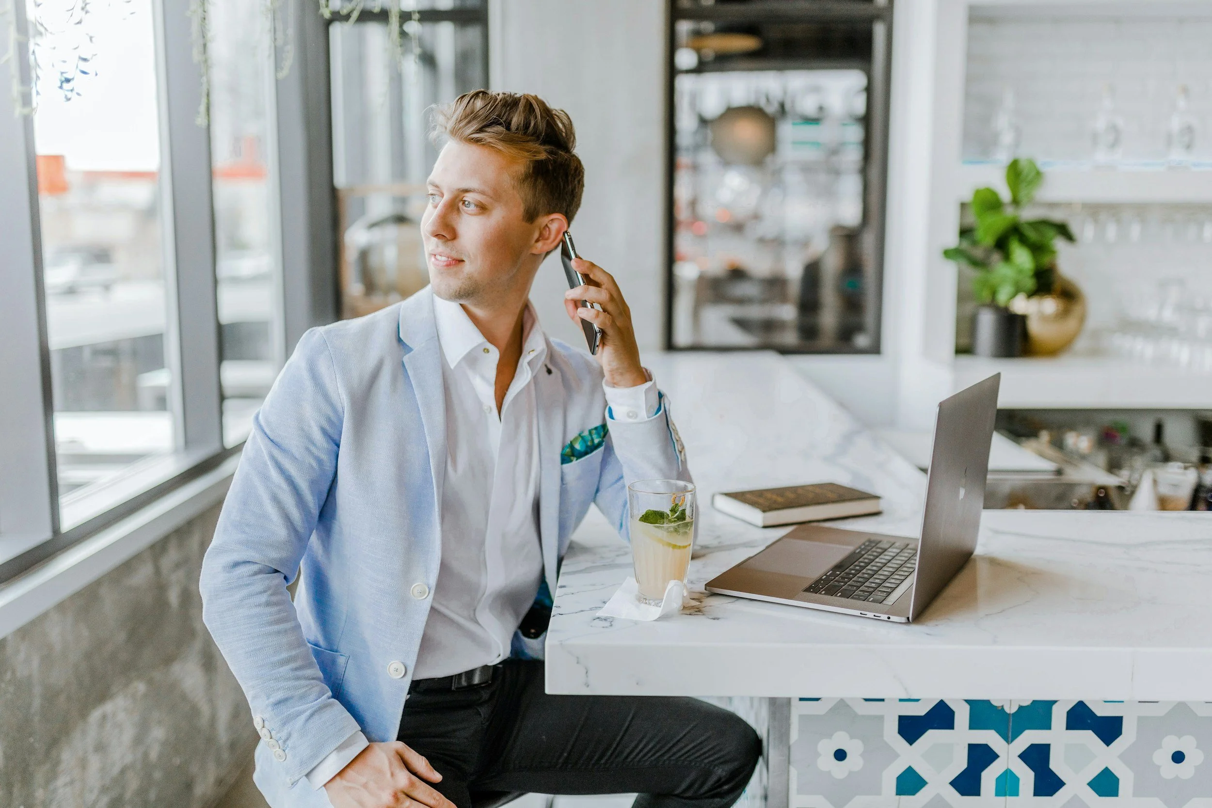 man working on his computer, talking on the phone, looking out window