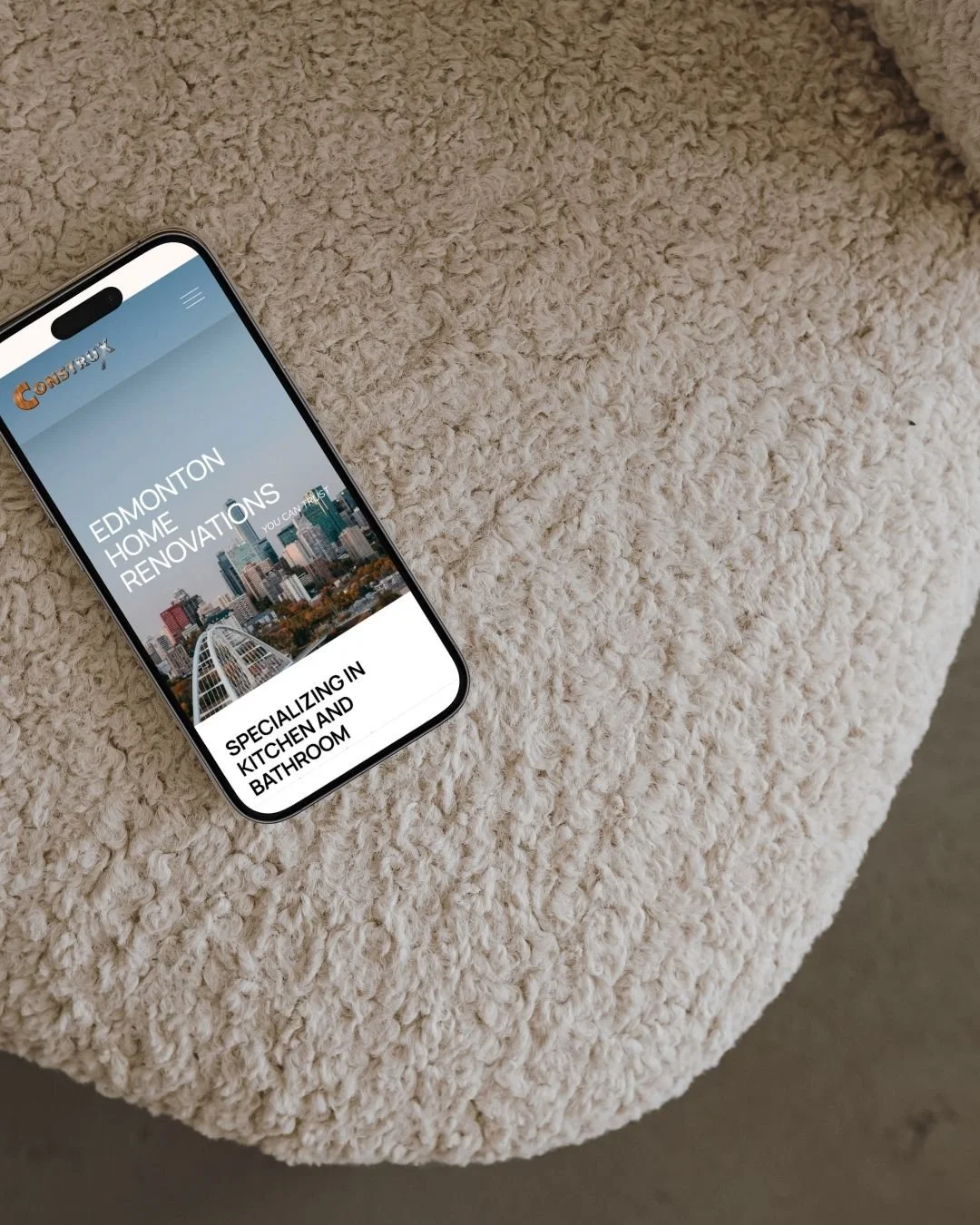 Phone showing Construx website on boucle chair.jpg