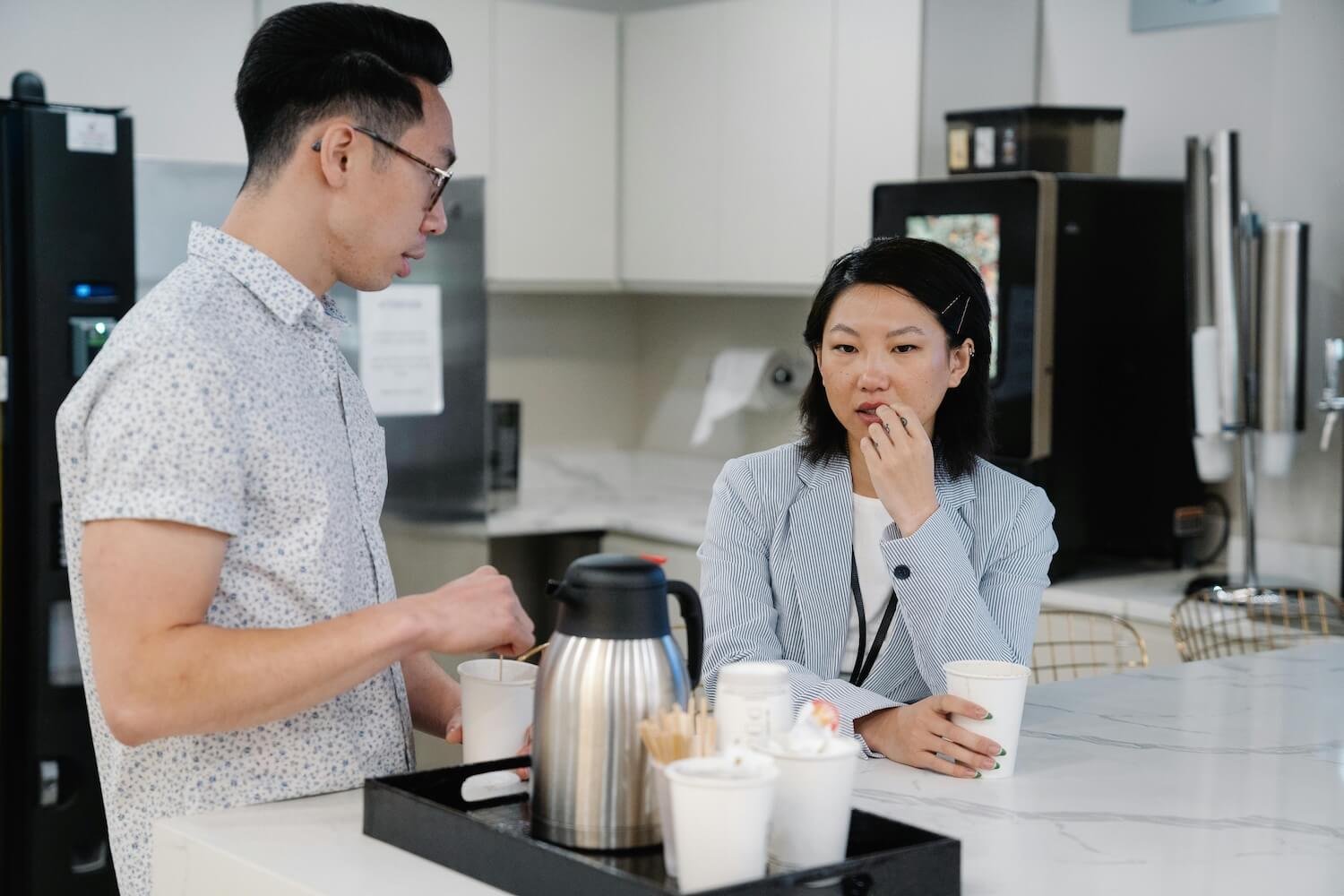Two people making coffee in an office kitchen