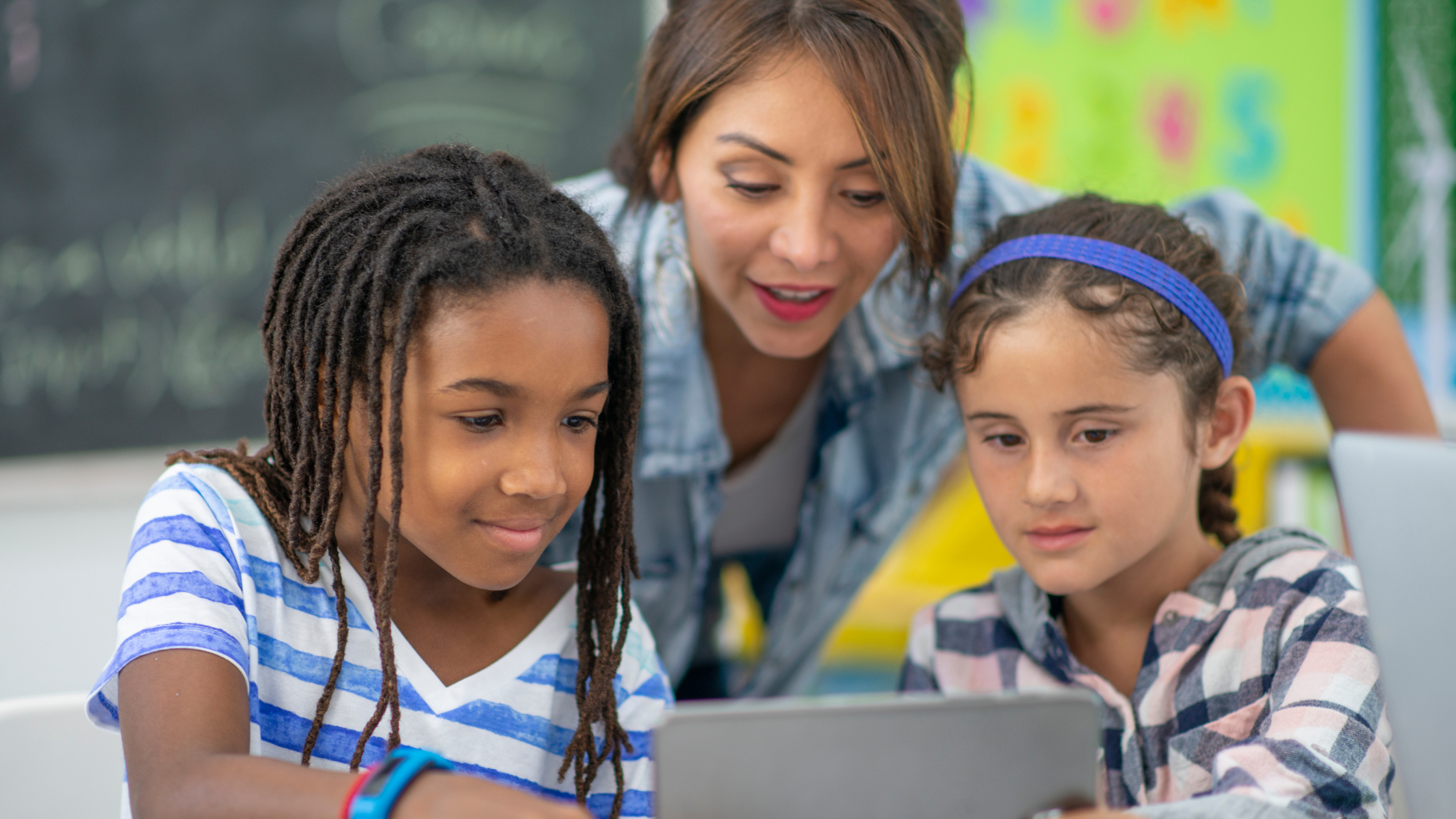 teacher and two students using a digital device