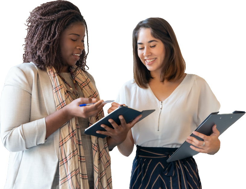 Two women co-workers discussing work, looking at a tablet, one holding a pen and the other holding a clipboard.
