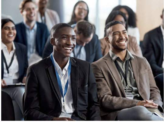 Group of diverse professionals attending a conference or seminar, smiling and engaging in the event.