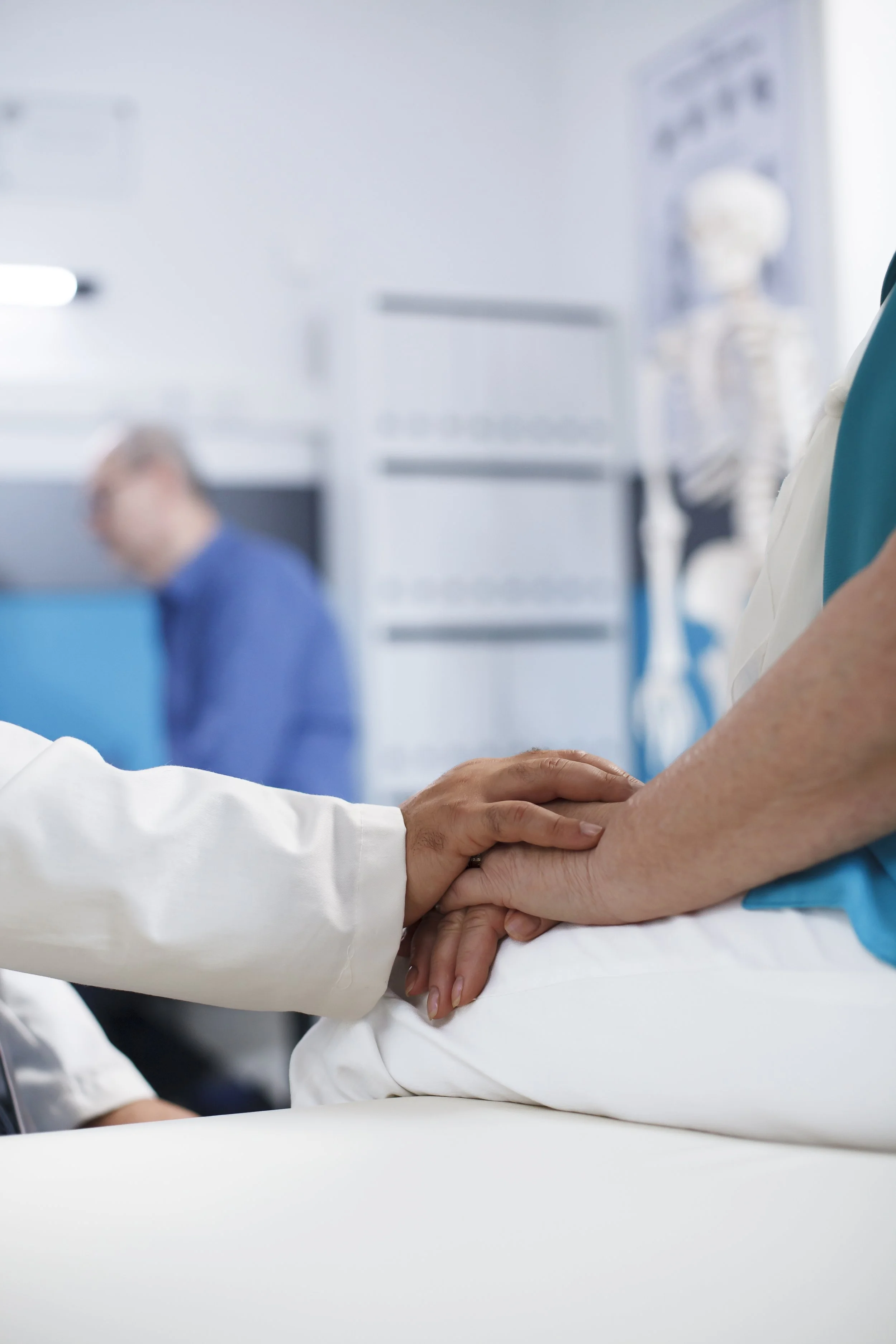 Healthcare professionals holding a patient's hand in a hospital setting. Credits for FreePik