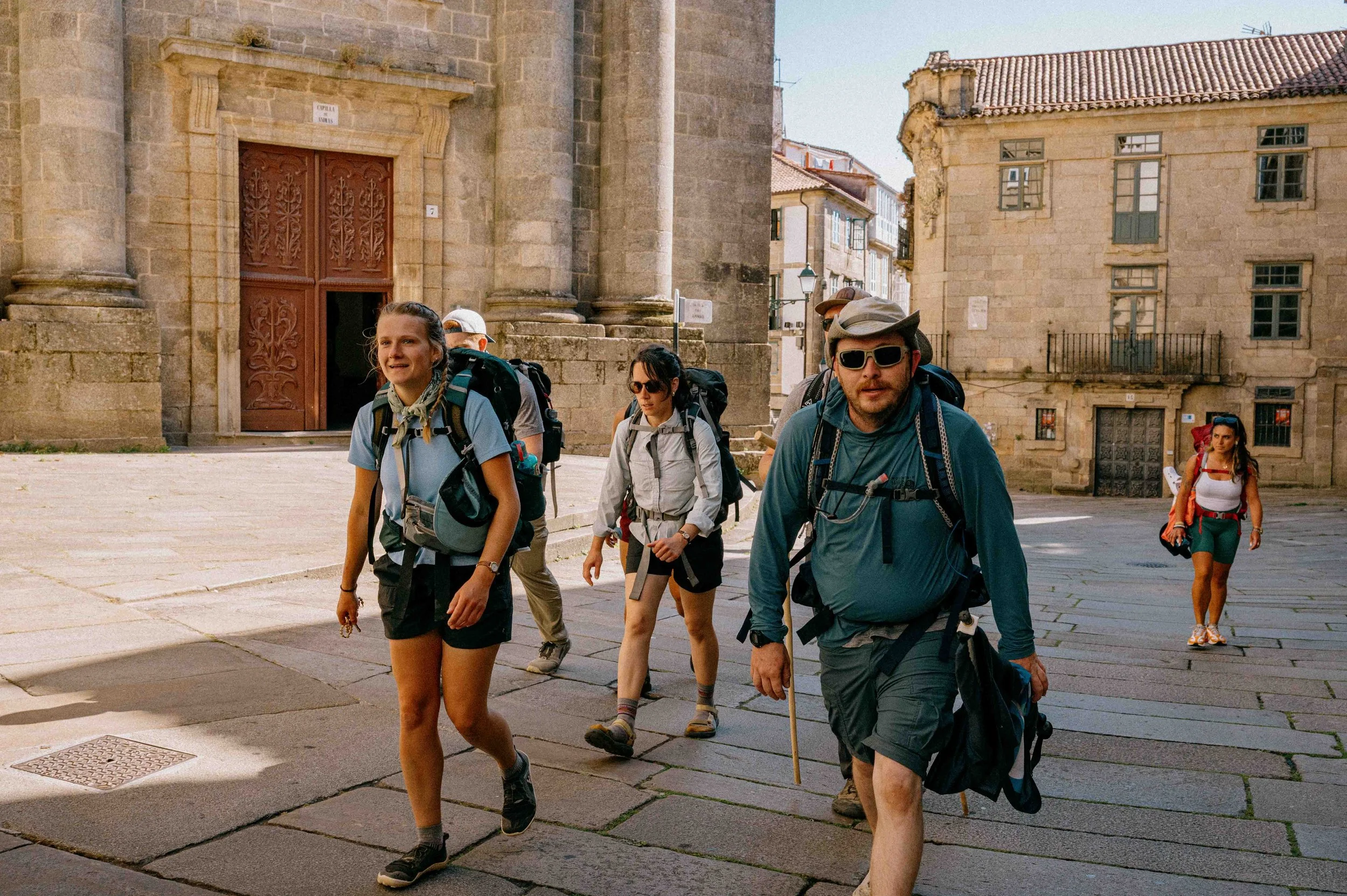 Group of hikers walking on a city street with historical buildings in the background