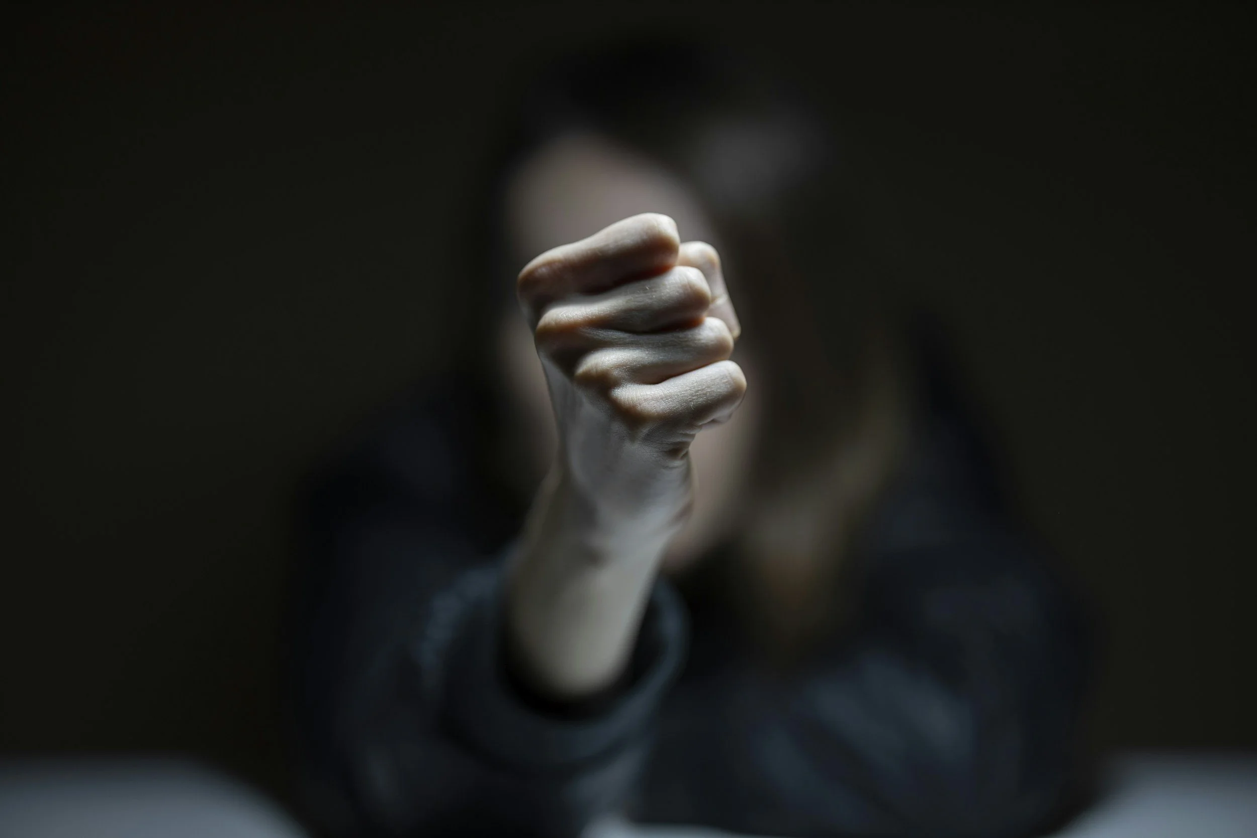 Woman raising her fist toward the camera, face blurred in the background
