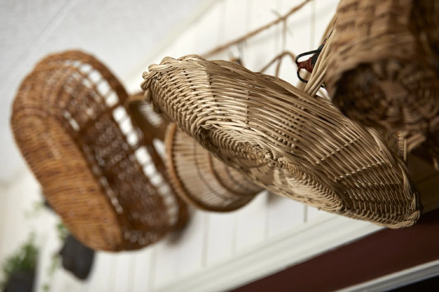 Wicker baskets hanging upside down on a white wall.