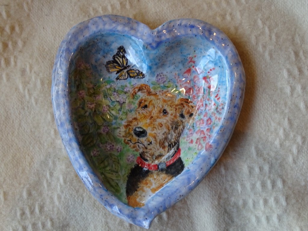 Decorative heart-shaped ceramic dish with a painting of a dog, butterfly, and floral background.