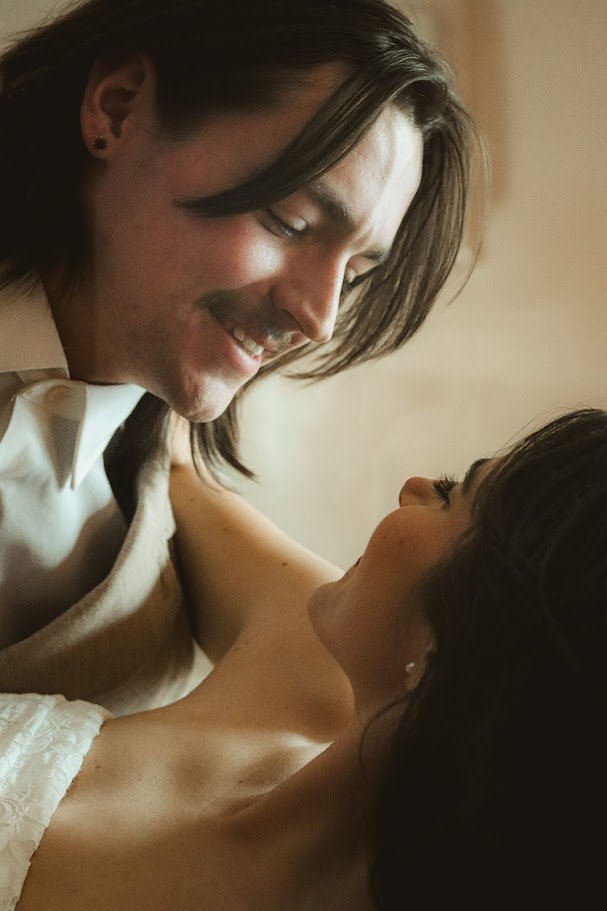 A man and a woman sharing an intimate moment, smiling and looking at each other.