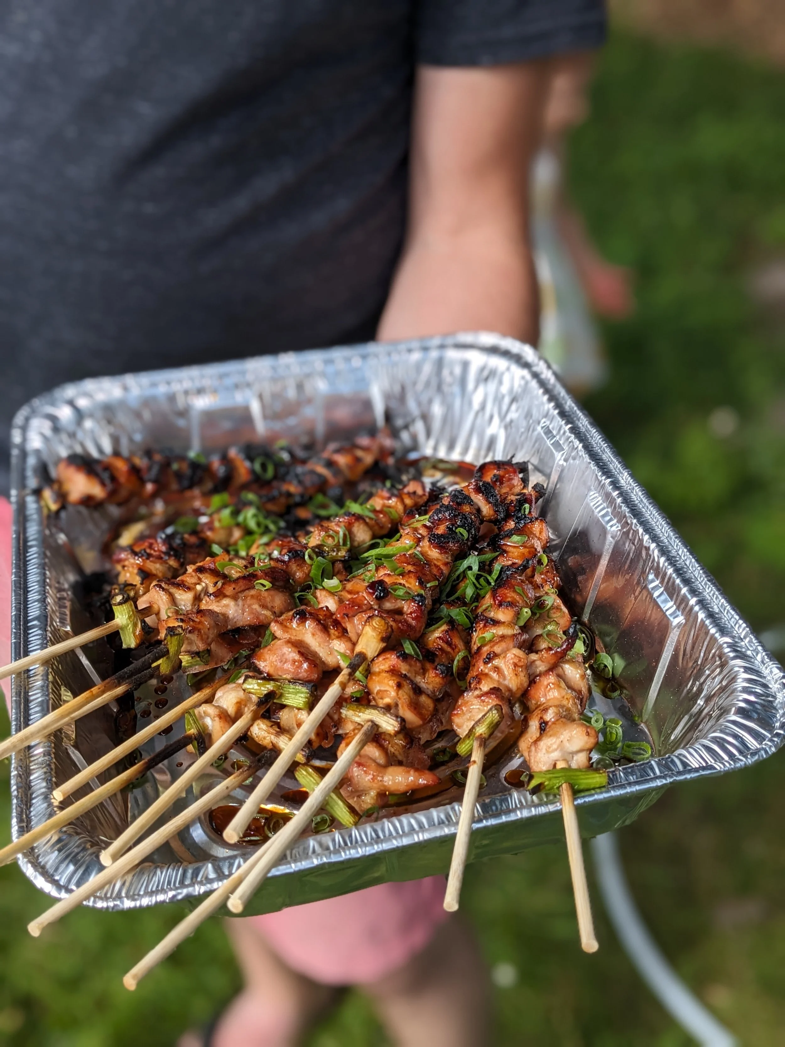 Chef Matthew holding a tray of chicken yakitori fresh off the grill