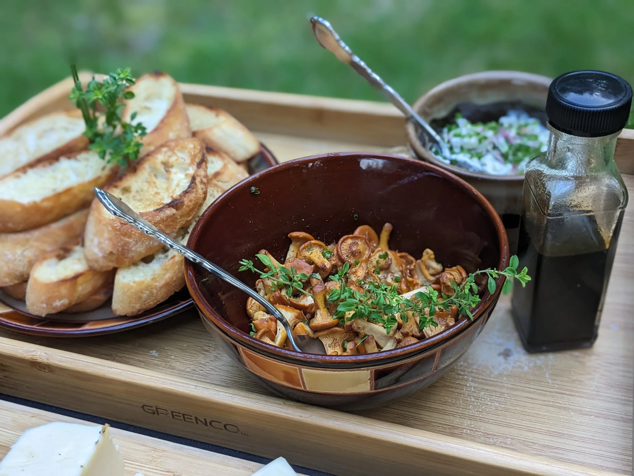 A bowl of roasted chanterelle mushrooms along with crostini and sauces