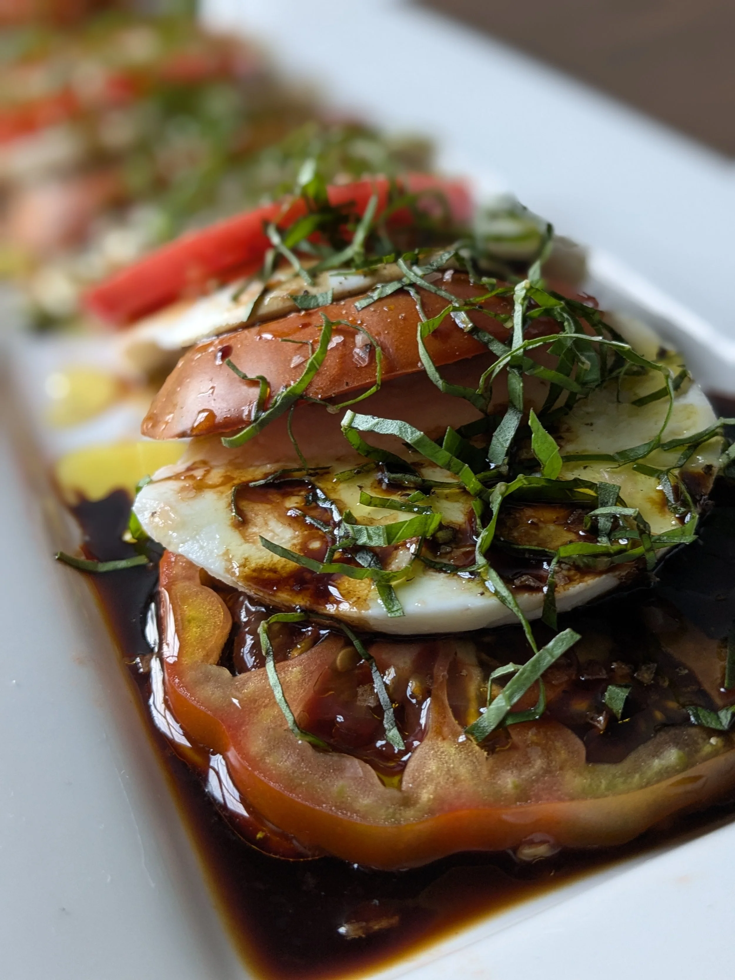 Sliced heirloom tomato and fresh mozzarella with basil, extra virgin olive oil, and balsamic
