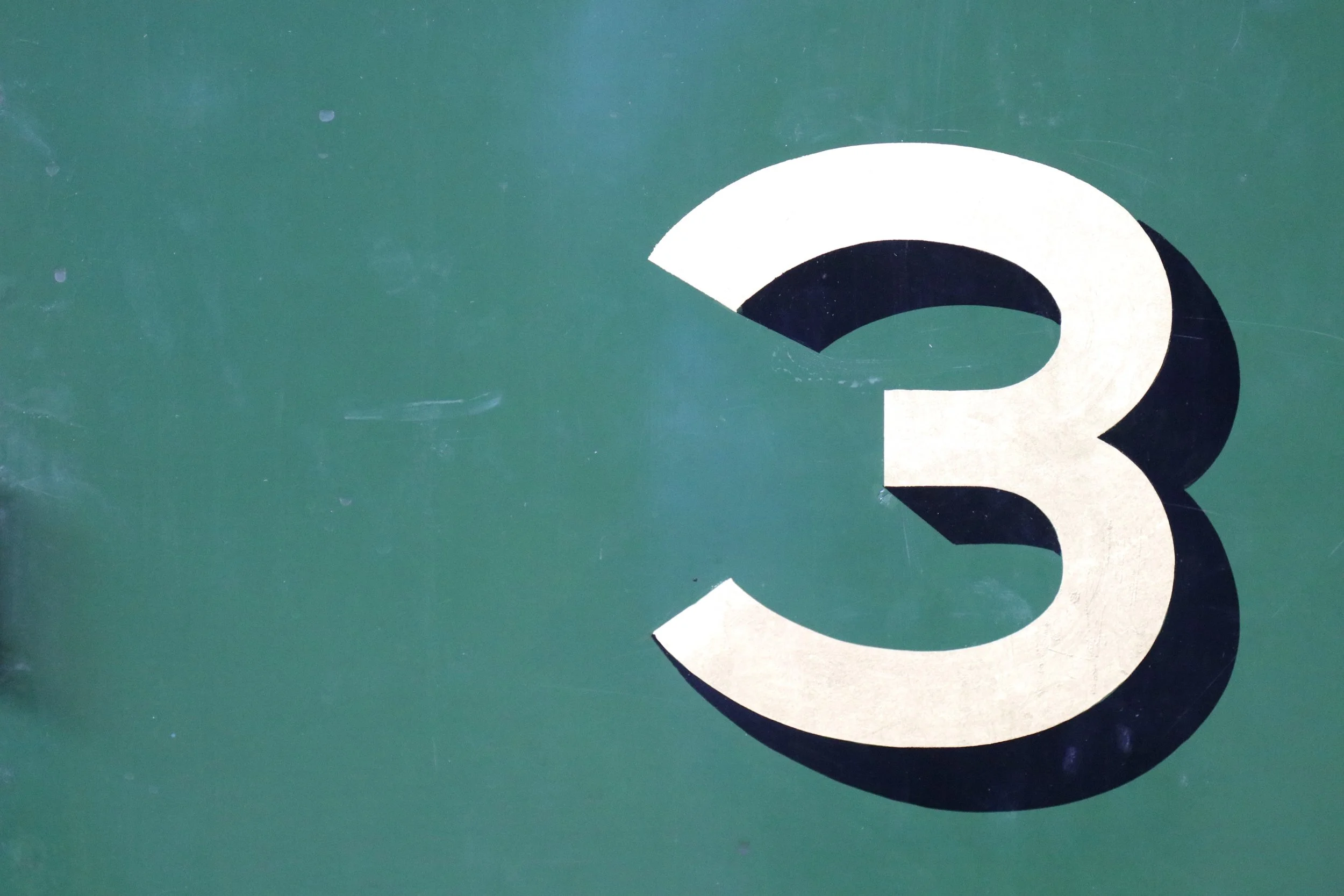 Close-up of a green surface with a partially visible large white and black letter or number.